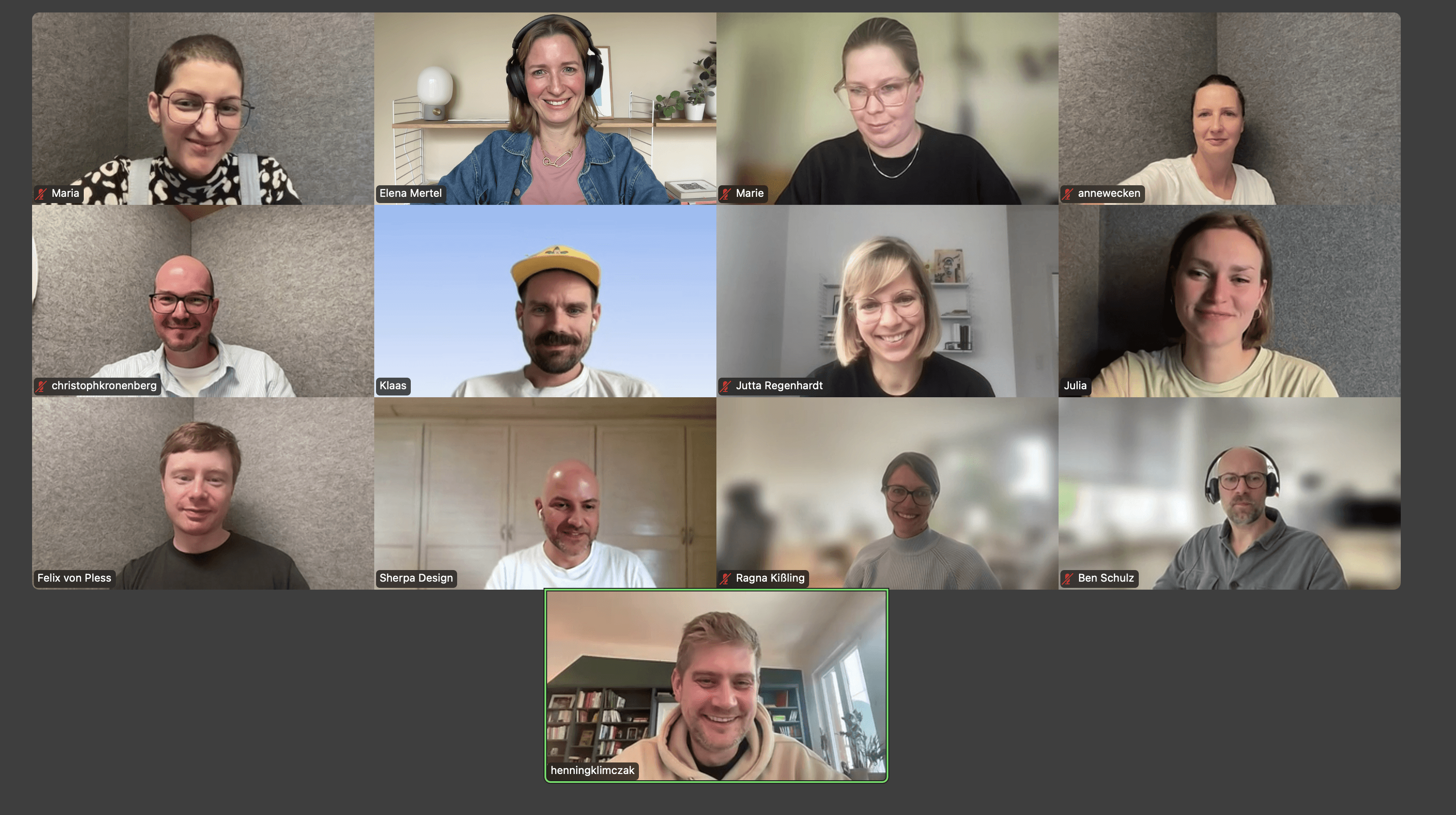 Smiling young man with curly hair, wearing a dark hoodie, against a softly lit background.