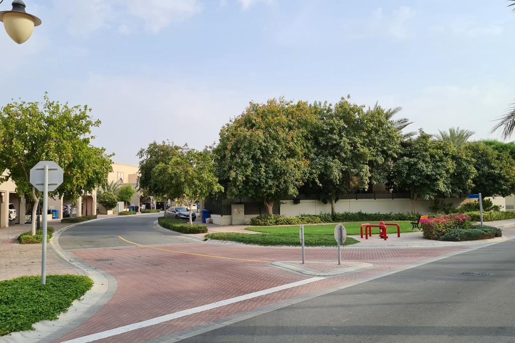 A quiet street in Cedre Villas, Dubai Silicon Oasis, with a stop sign and tree.