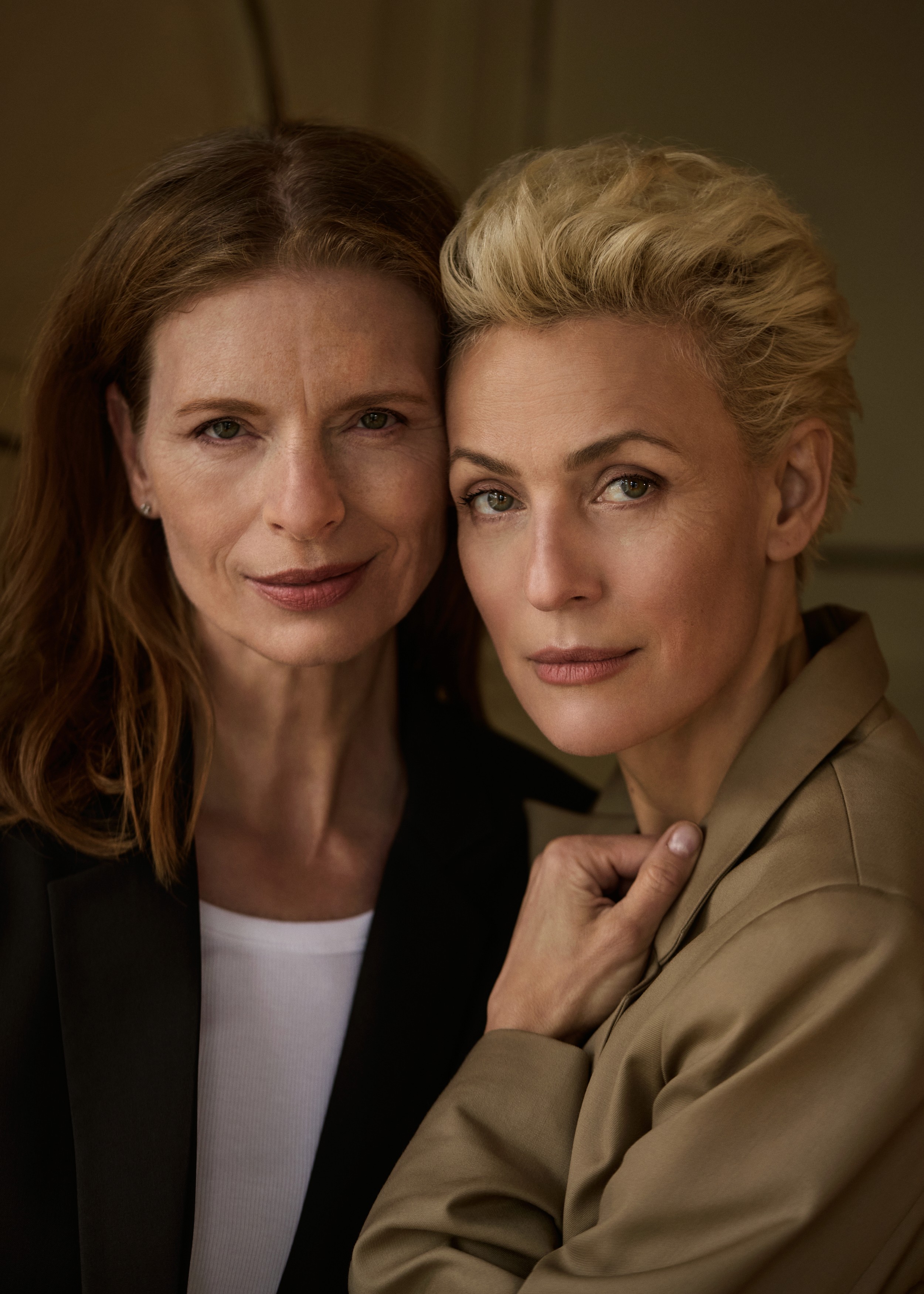 Woman in a light green long-sleeved dress holding a small cream-colored leather handbag with gold hardware in both hands.