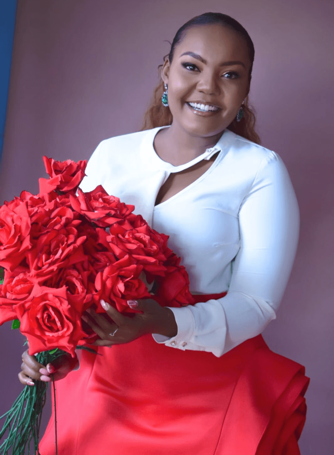 A woman with long dark hair wearing a black hijab, looking calmly at the camera against a muted background.