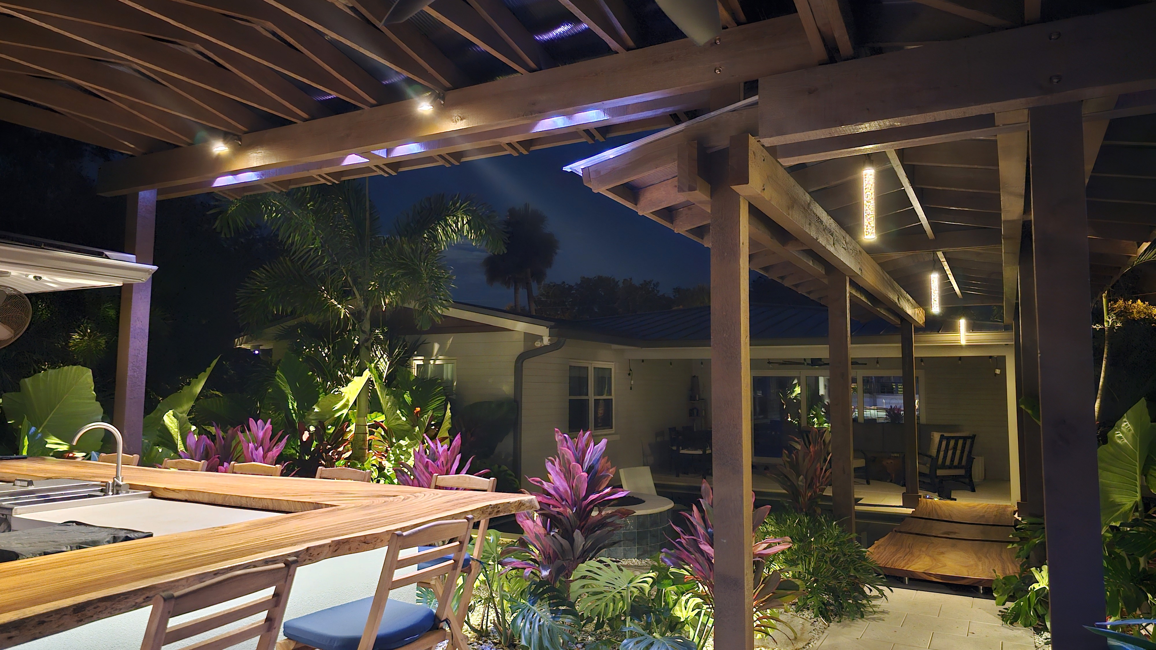 Wood-beam pergola and outdoor dining space illuminated with warm lighting