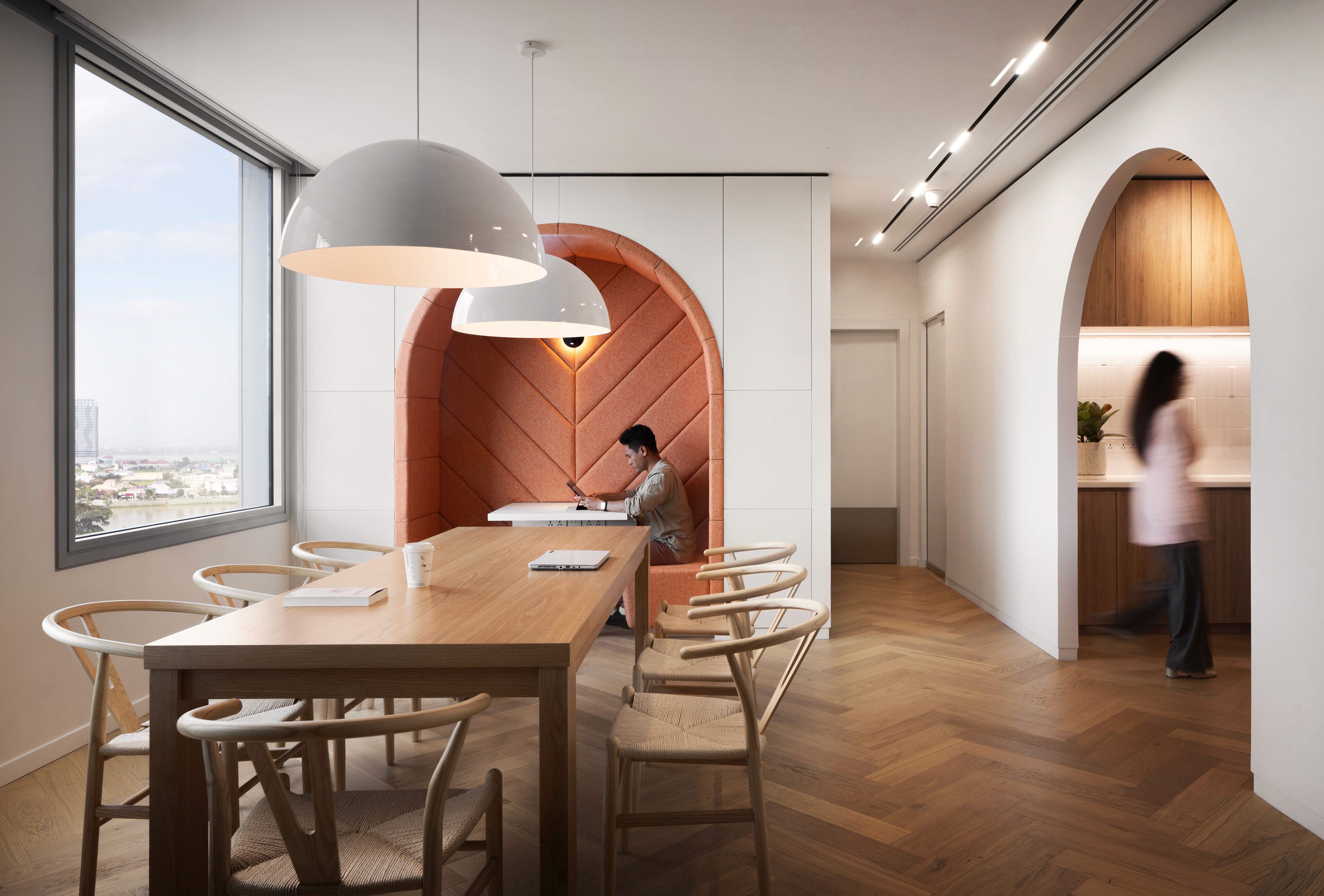 Modern office interior at Exchange Square Phnom Penh with oak communal table and arched terracotta meeting pod.