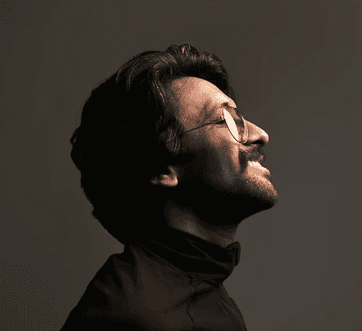 a man with glasses looking up into the sky