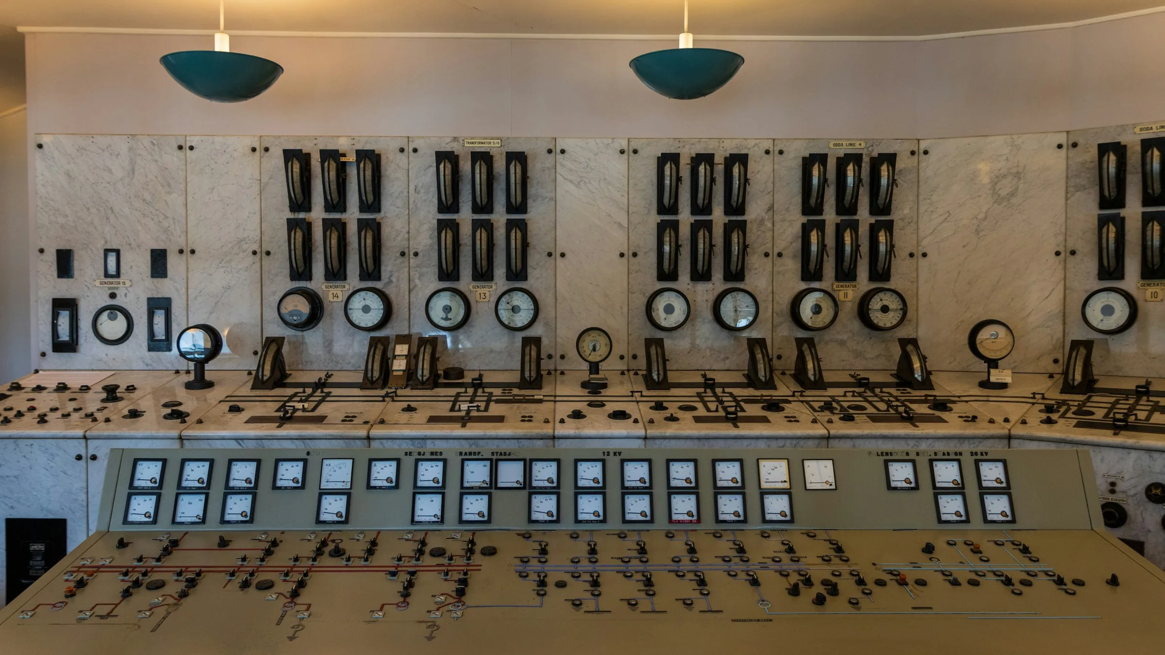 An industrial control room with rows of gauges and switches