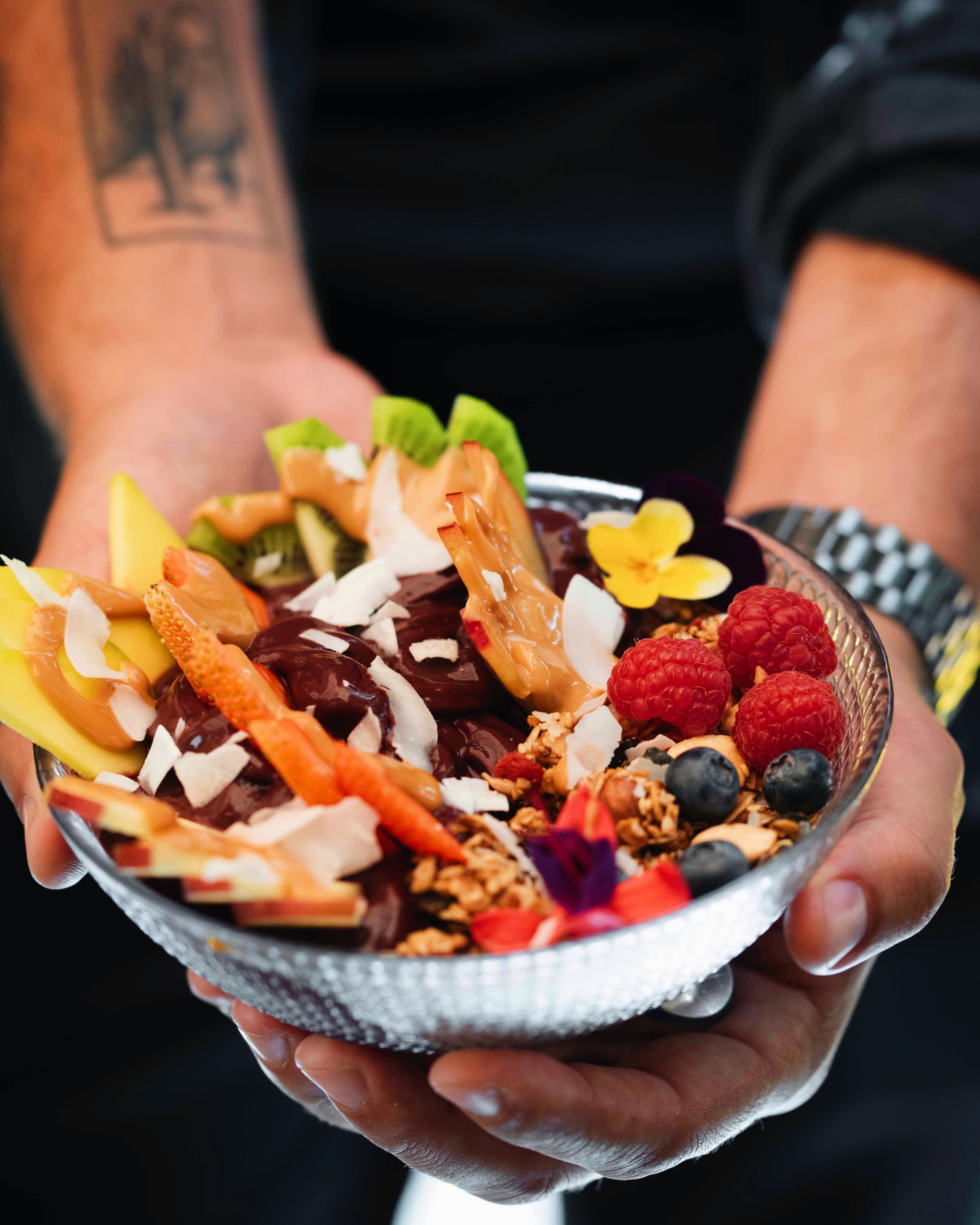 Açaí bowl with granola, fresh raspberries, coconut, mango and edible flowers — vegan brunch option at Faire. Brunch & Drinks, Eixample Barcelona