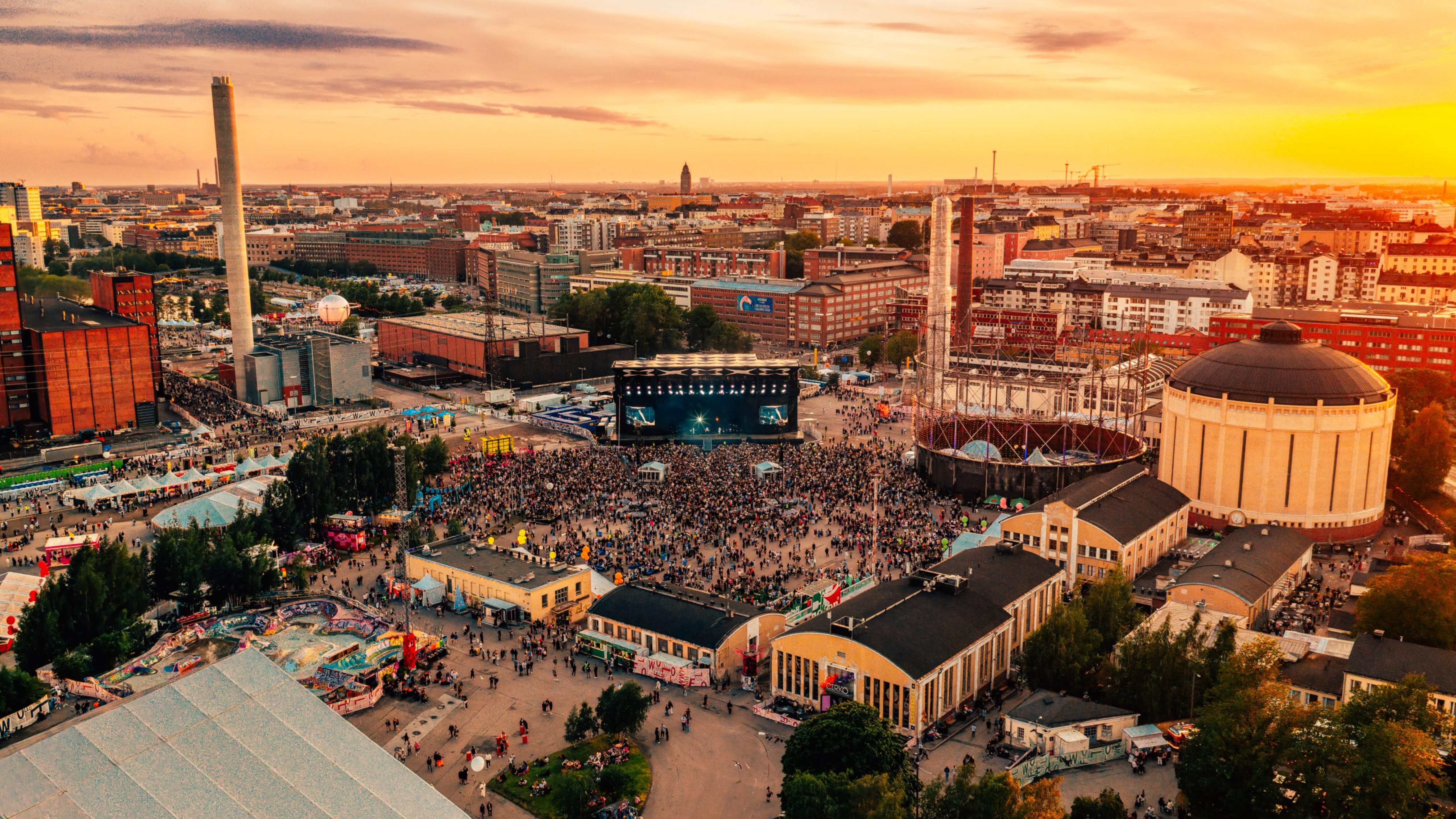 Crowds gathered around outdoor concert stages at Flow Festival during sunset in Helsinki.