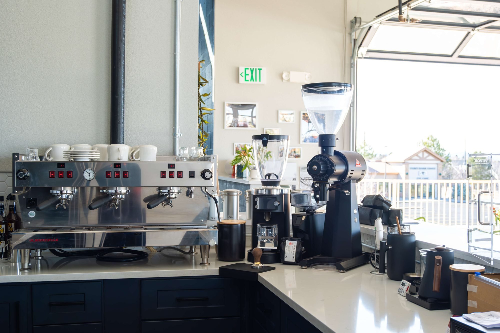 The espresso machine and grinder on the counter by the window
