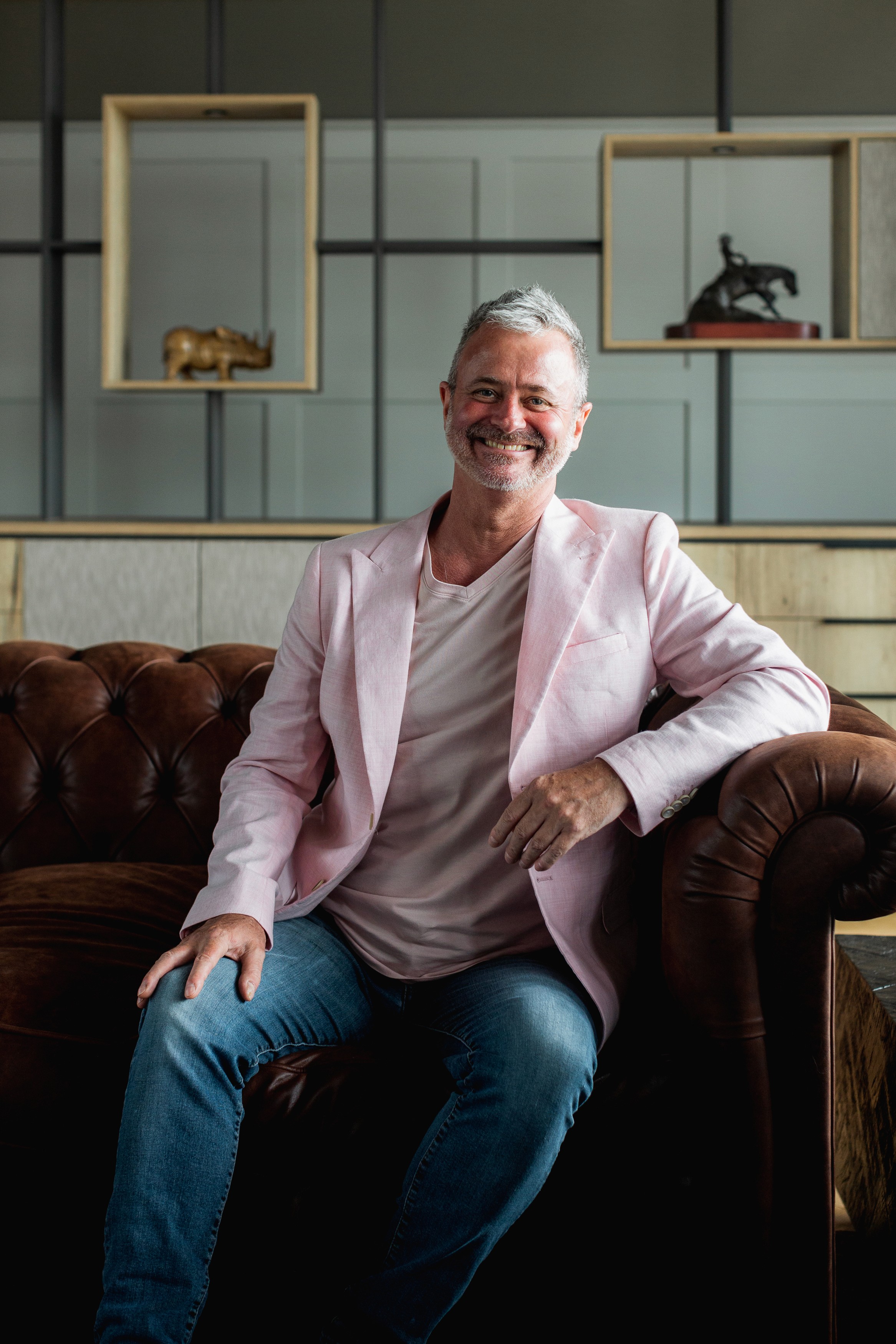 Woman in a light suit sitting thoughtfully against a terracotta wall