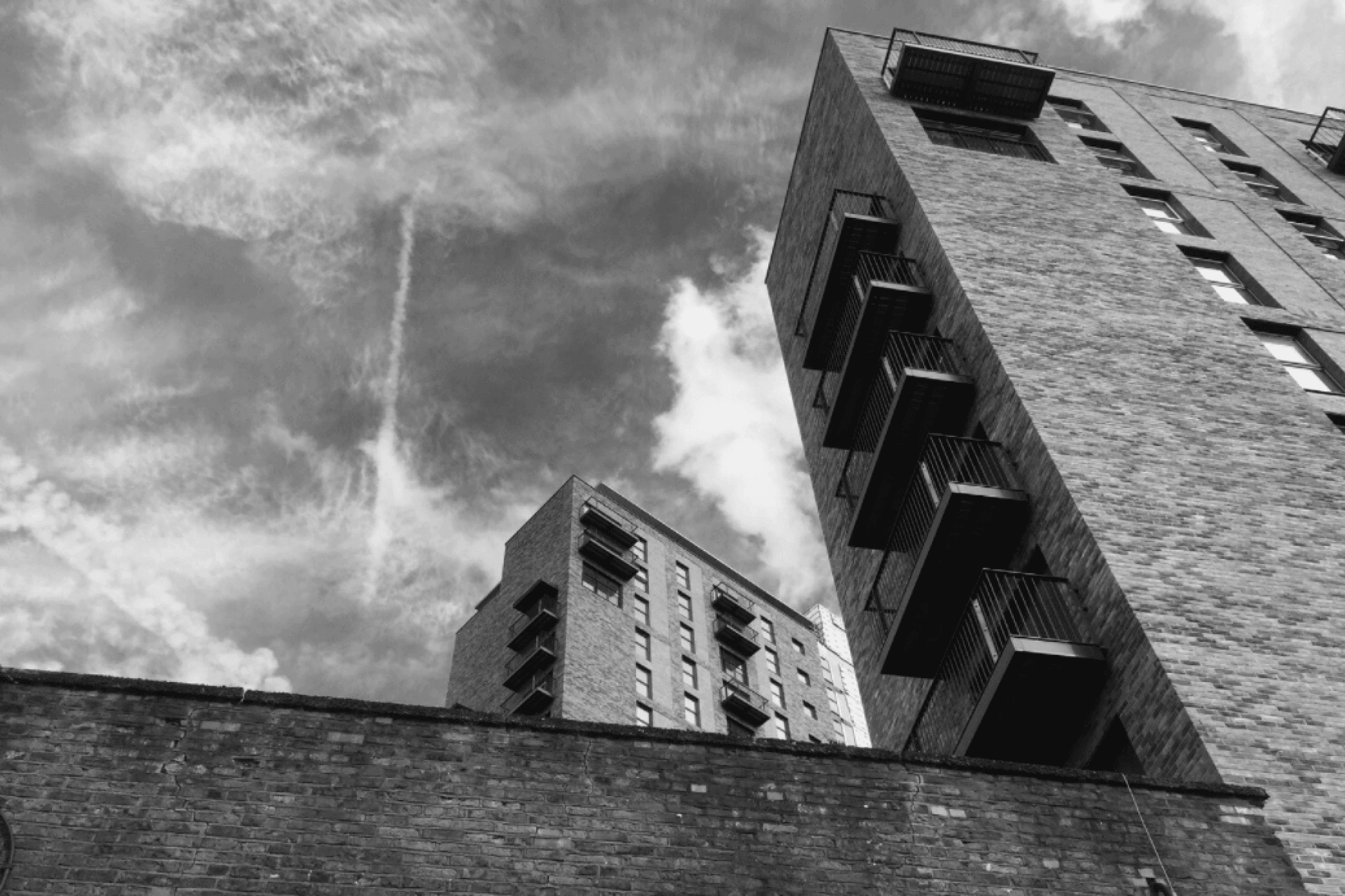 A black and white photo looking upward to some buildings and the sky