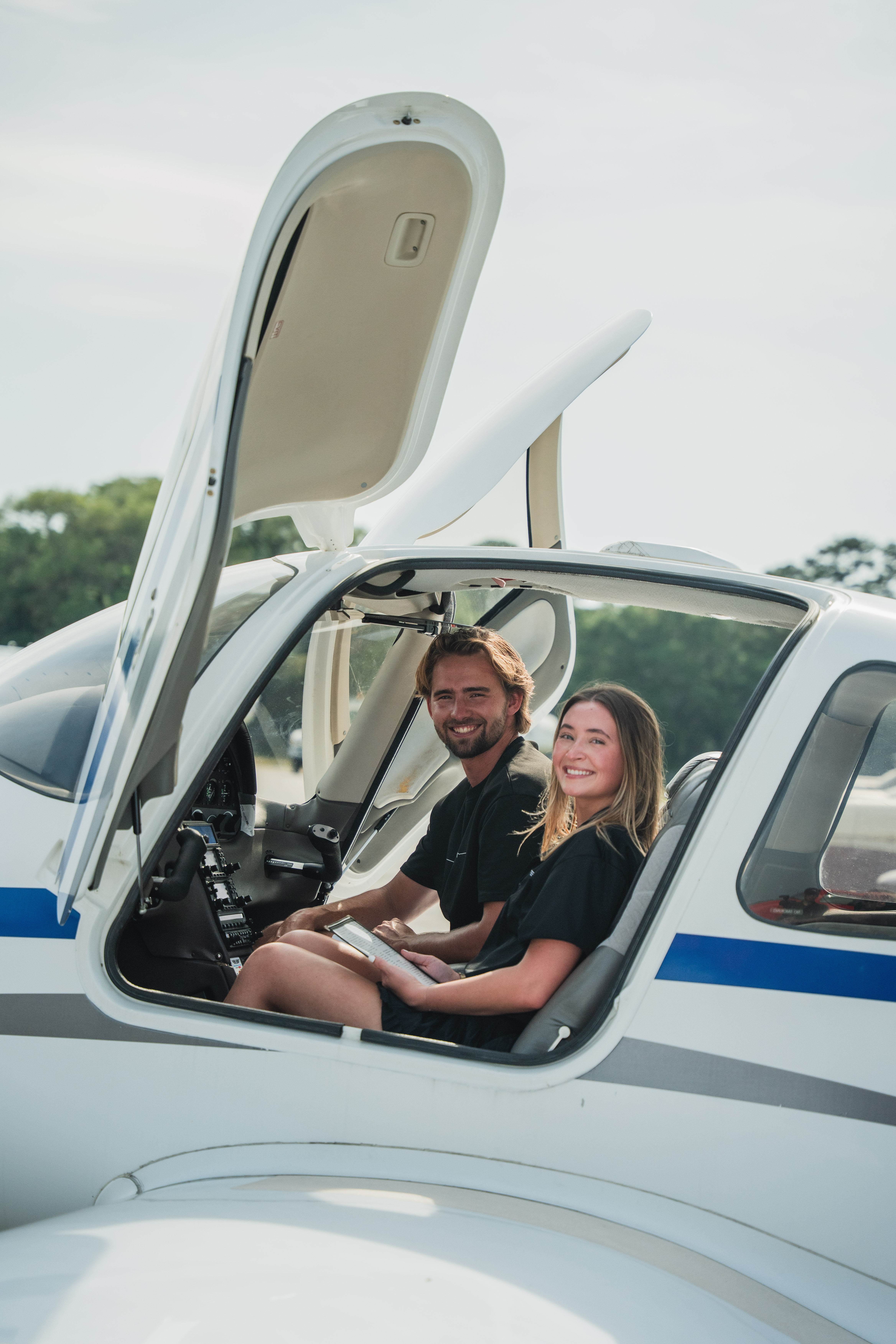 Man wearing headphones and a white t-shirt working on a laptop in soft natural light, with window shadows cast on the wall.