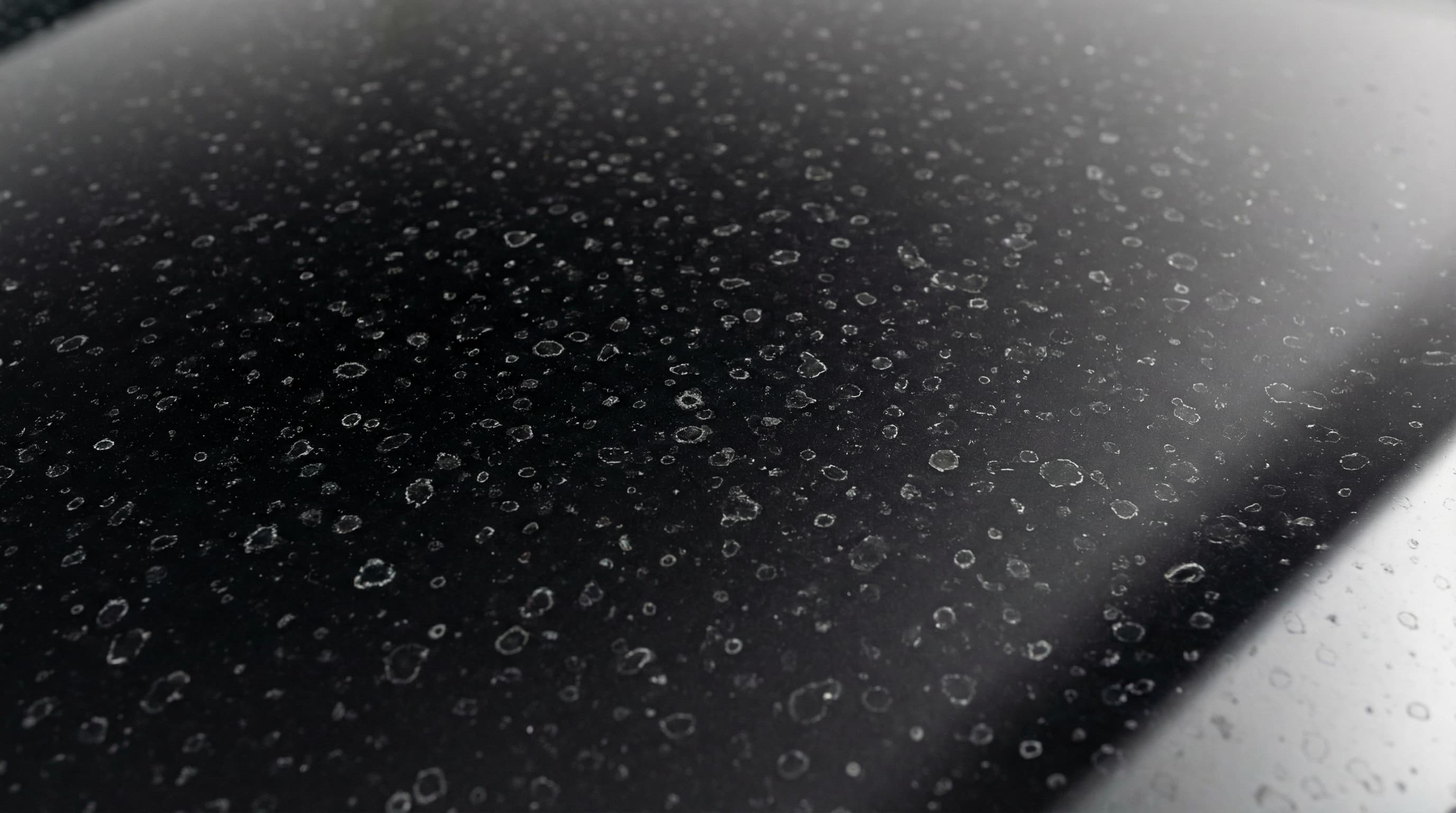 Traces de calcaire sur une carrosserie noire en gros plan