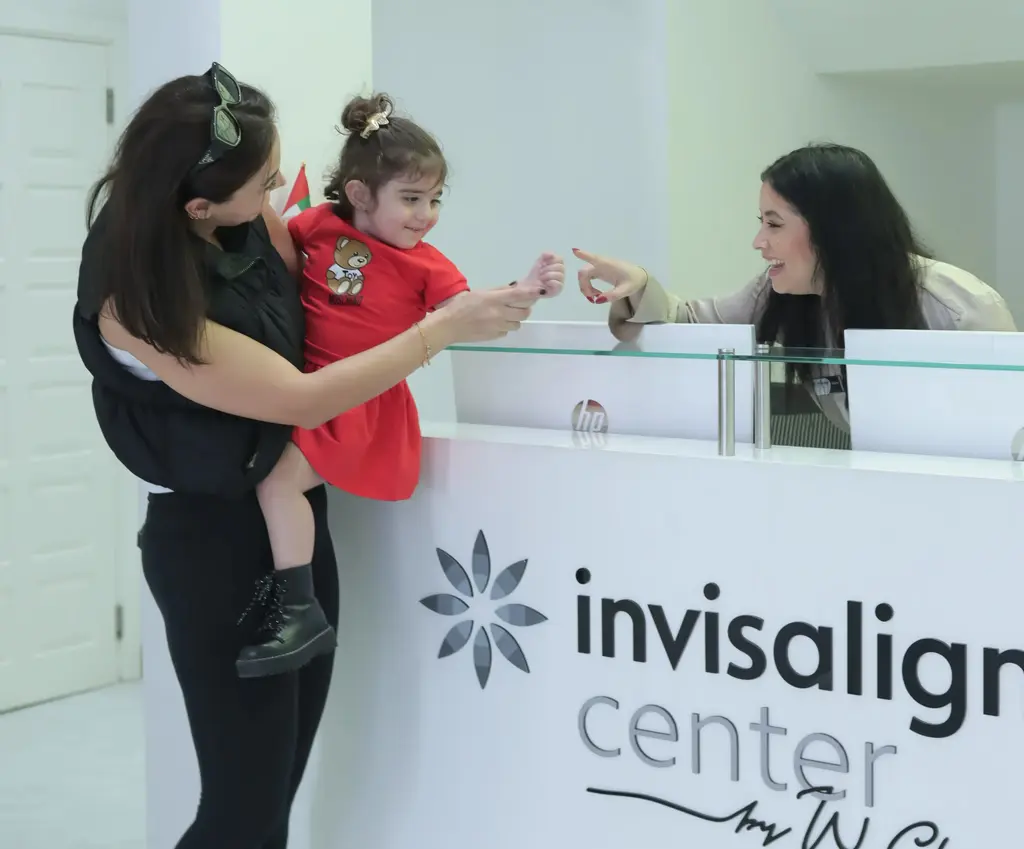 استقبال ودي لطفلة ووالدتها في العيادة تمهيداً لحجز موعد فحص دوري للكشف المبكر عن تسوس أسنان الأطفال.