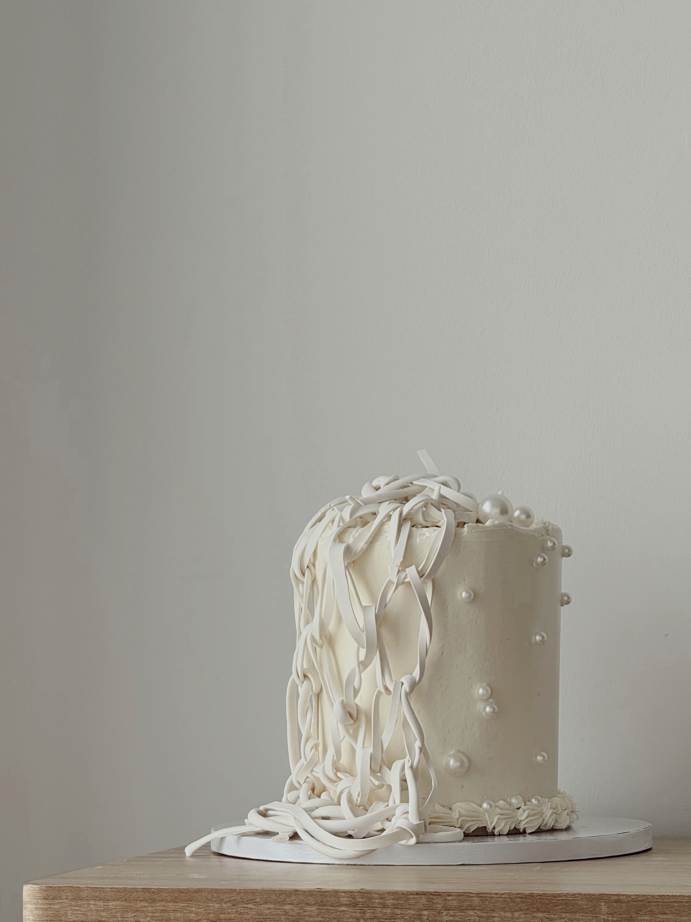 Tall white buttercream cake with cascading ribbon-style piping