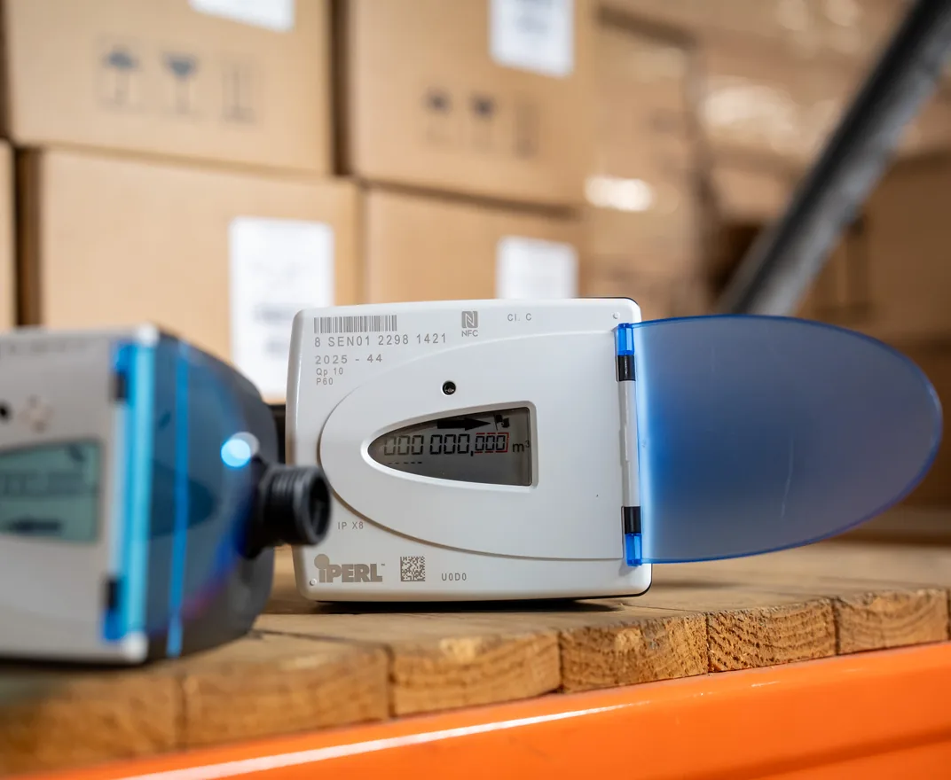 Two Sensus iPERL smart water meters on a shelf in the JOAT warehouse