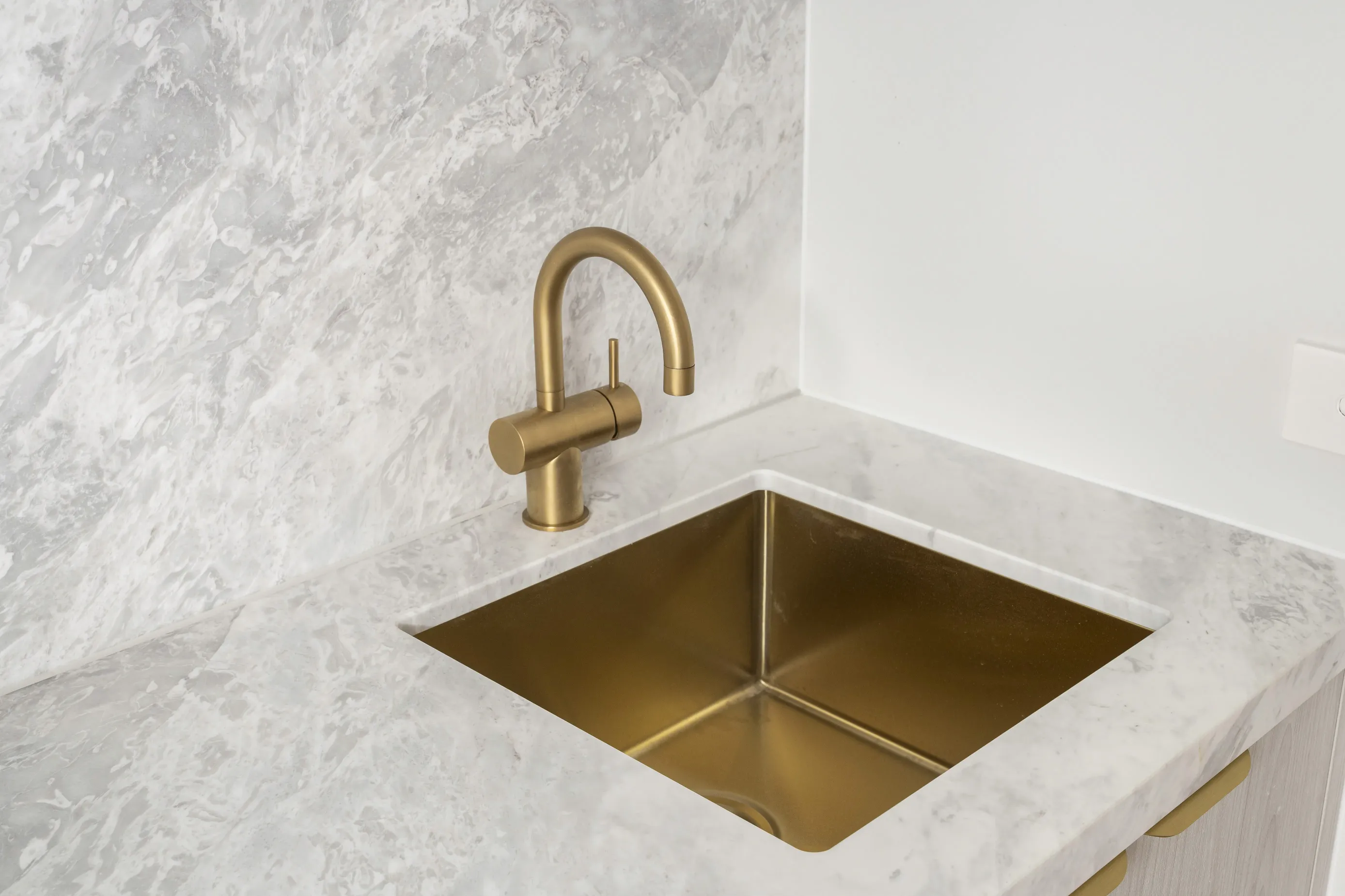 Detail of a brushed-brass undermount bar sink and matching tap set into a marble benchtop at Bundoora