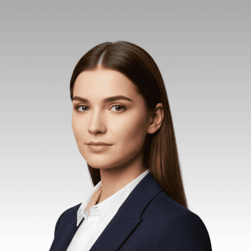 A professional portrait of a woman with dark hair wearing a blazer and white shirt, looking directly at the camera.