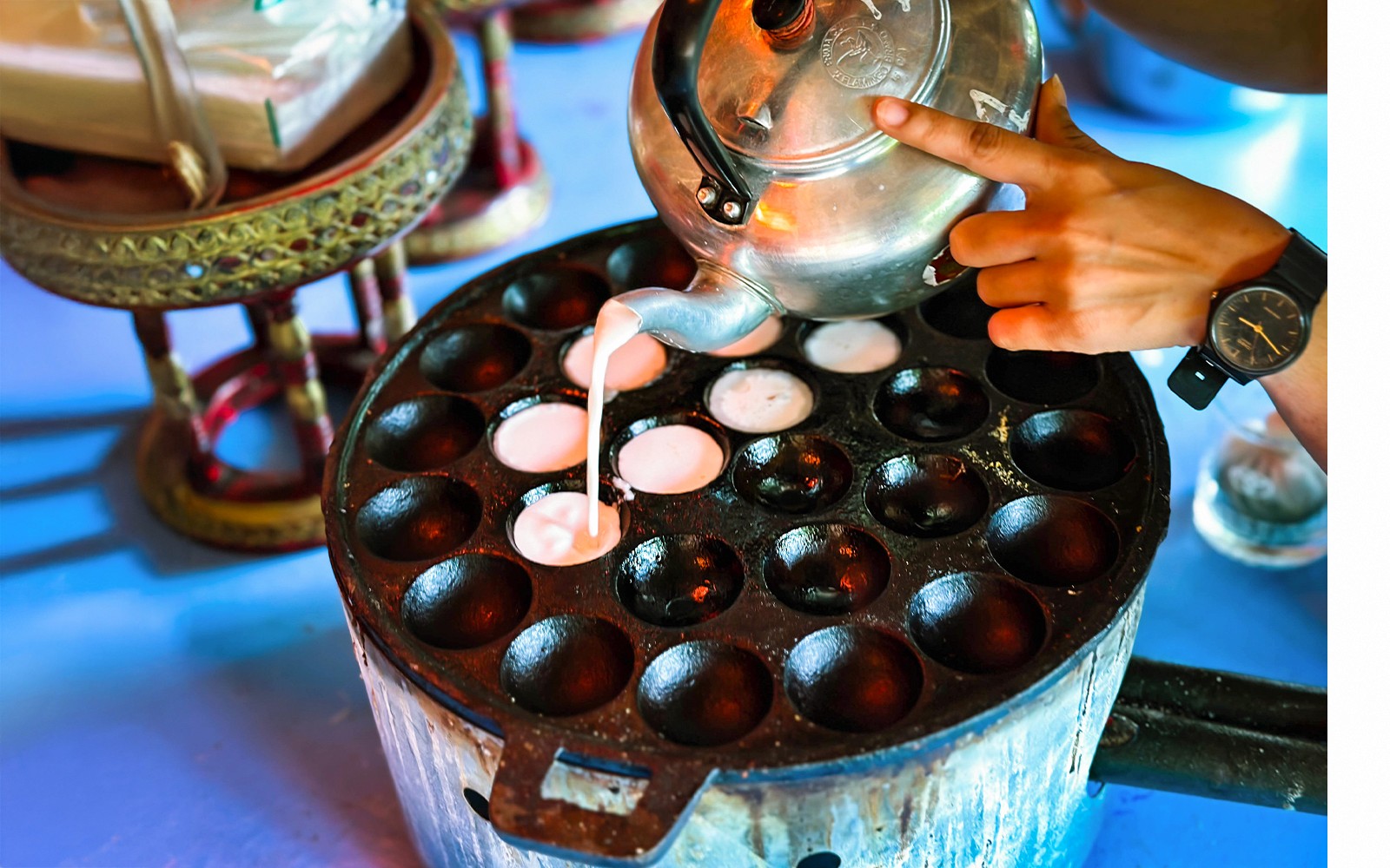 Menuangkan adunan ke dalam kuali kanom krok Thai di Phuket.