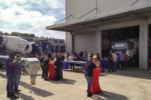 A person wearing a virtual reality headset and a white sweater holds one hand up in a futuristic gesture, standing against a grid-patterned background.