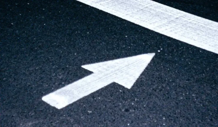 Illustration d'une flèche blanche pointant vers le haut à droite sur une route goudronnée, symbolisant la croissance et l'ascension.