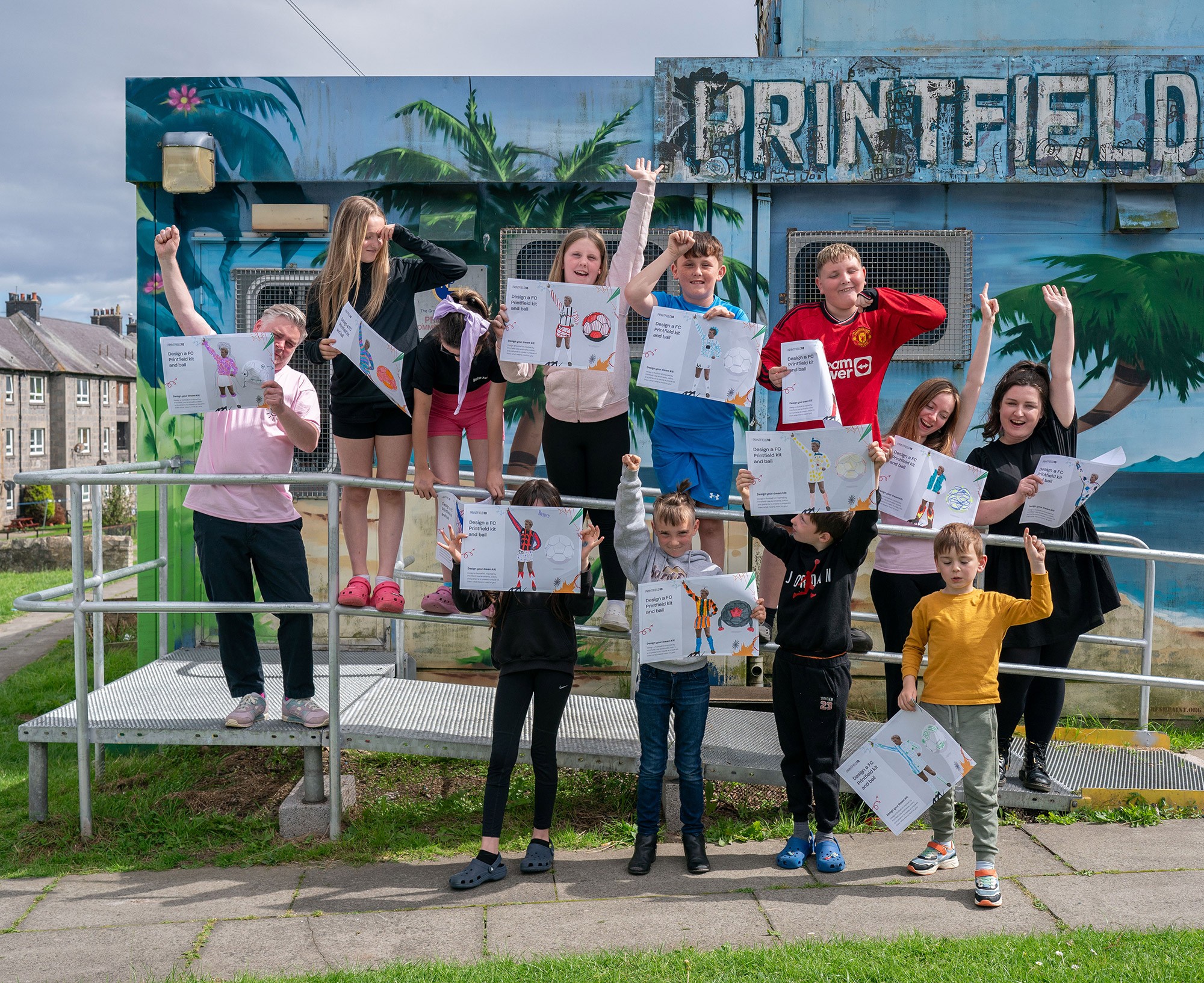 A group of kids holding artwork up from a workshop