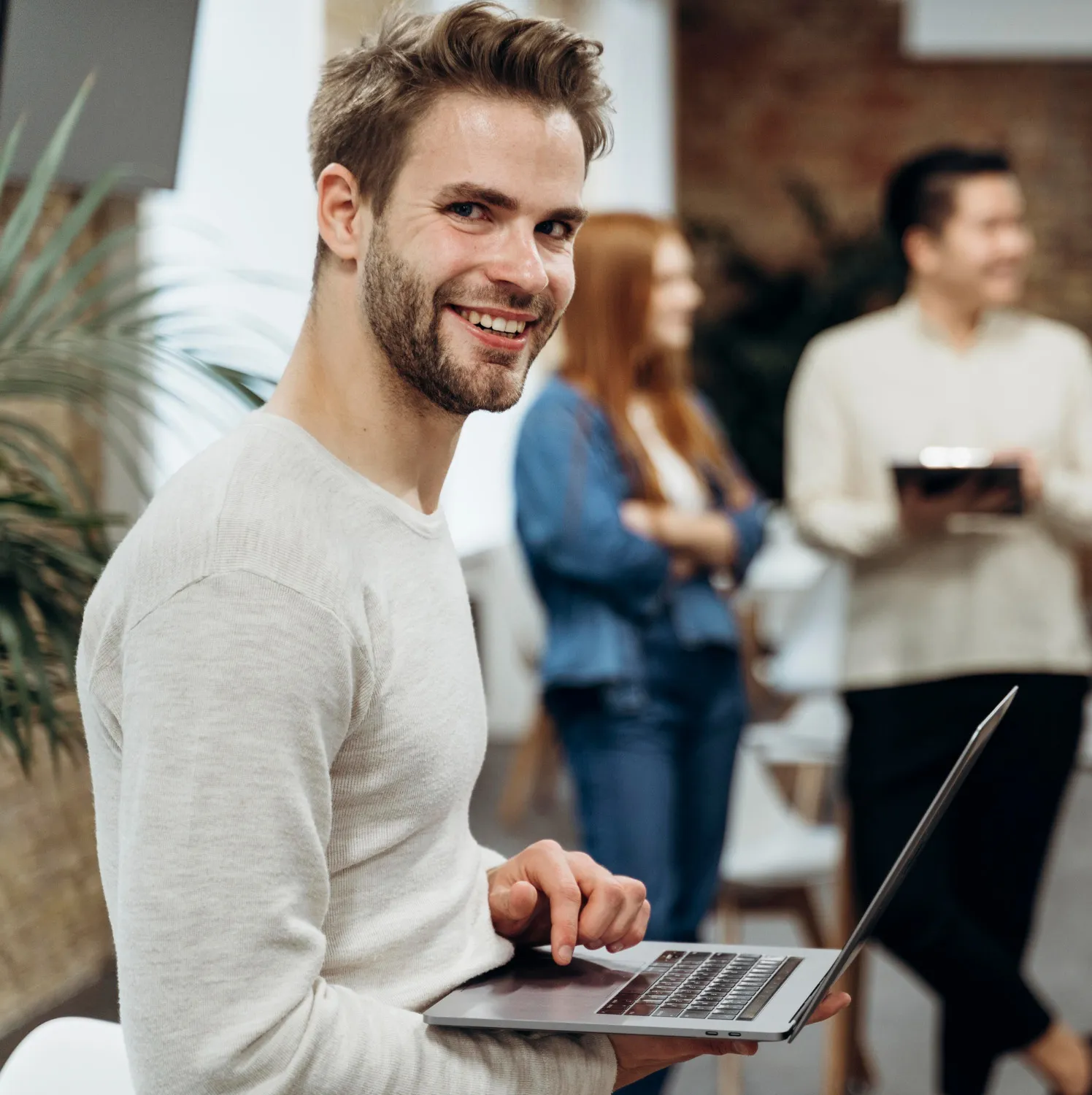 IT specialist standing with a laptop during an informal team meeting.