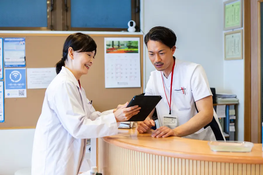 AI in pharmacy discussed by healthcare professionals reviewing digital tablet at clinic reception desk.