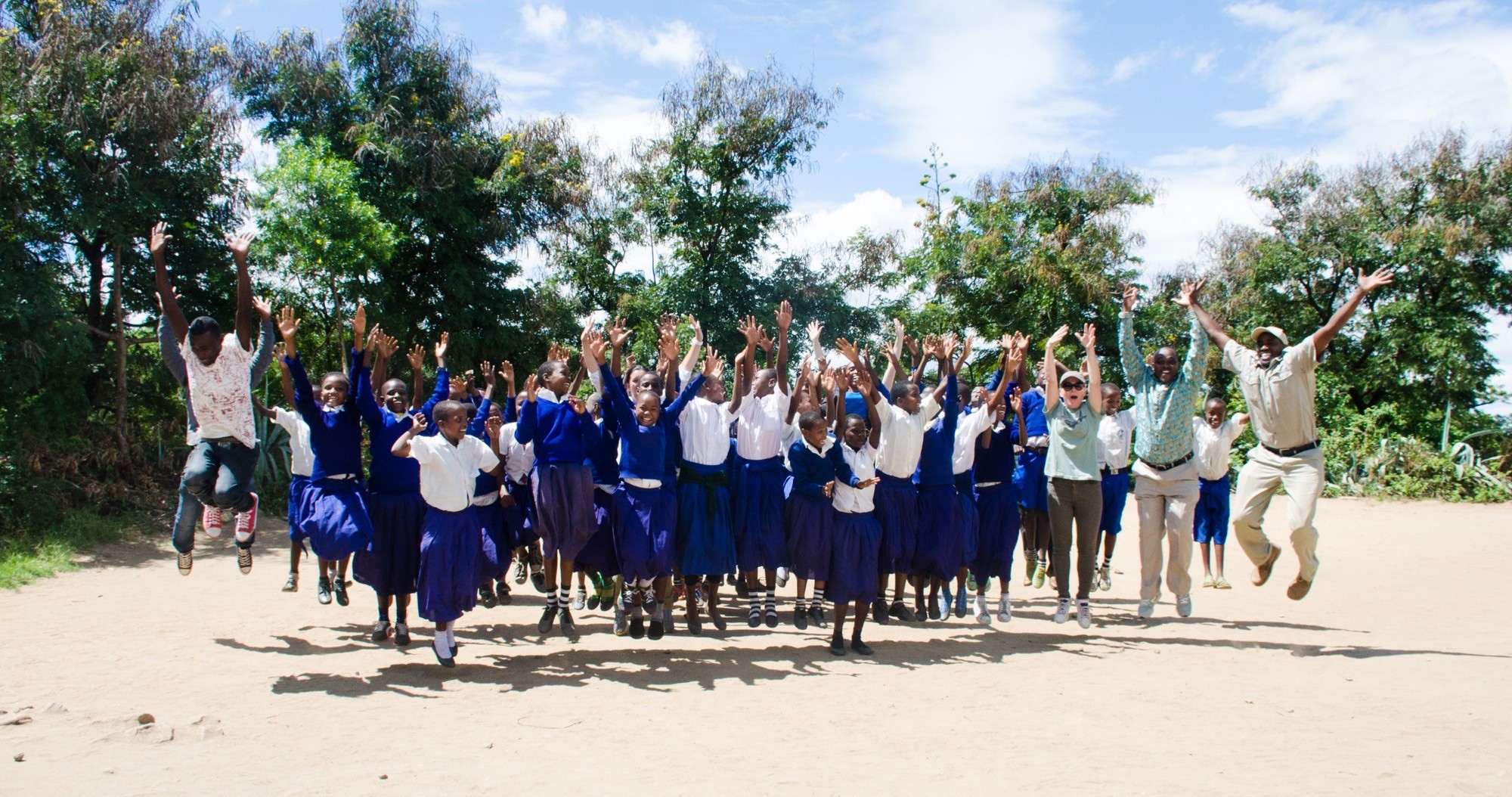 Schoolchildren and teachers leaping in the air together during a community foundation visit