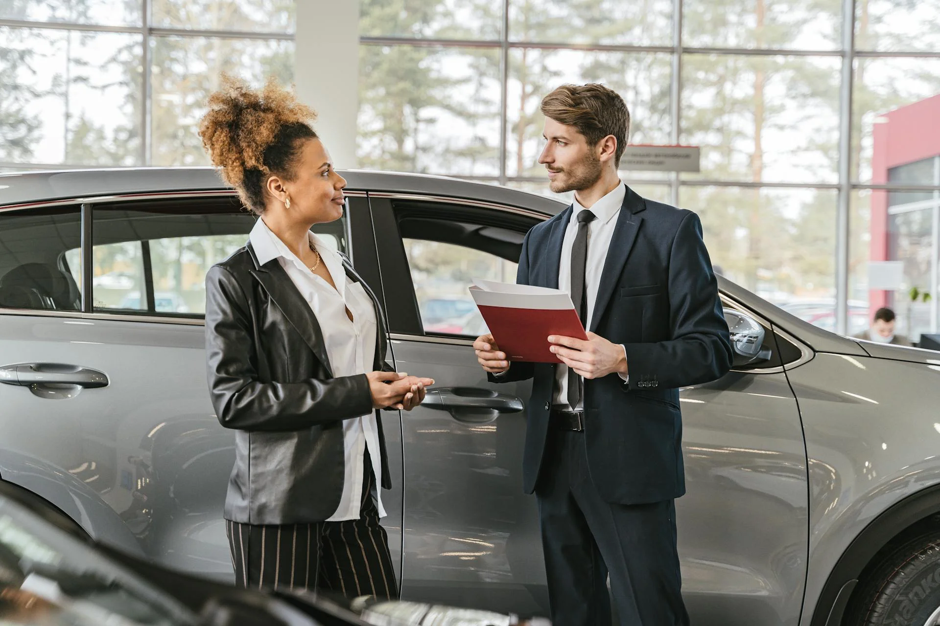 Car dealership staff discussing vehicle details with a customer inside a modern showroom