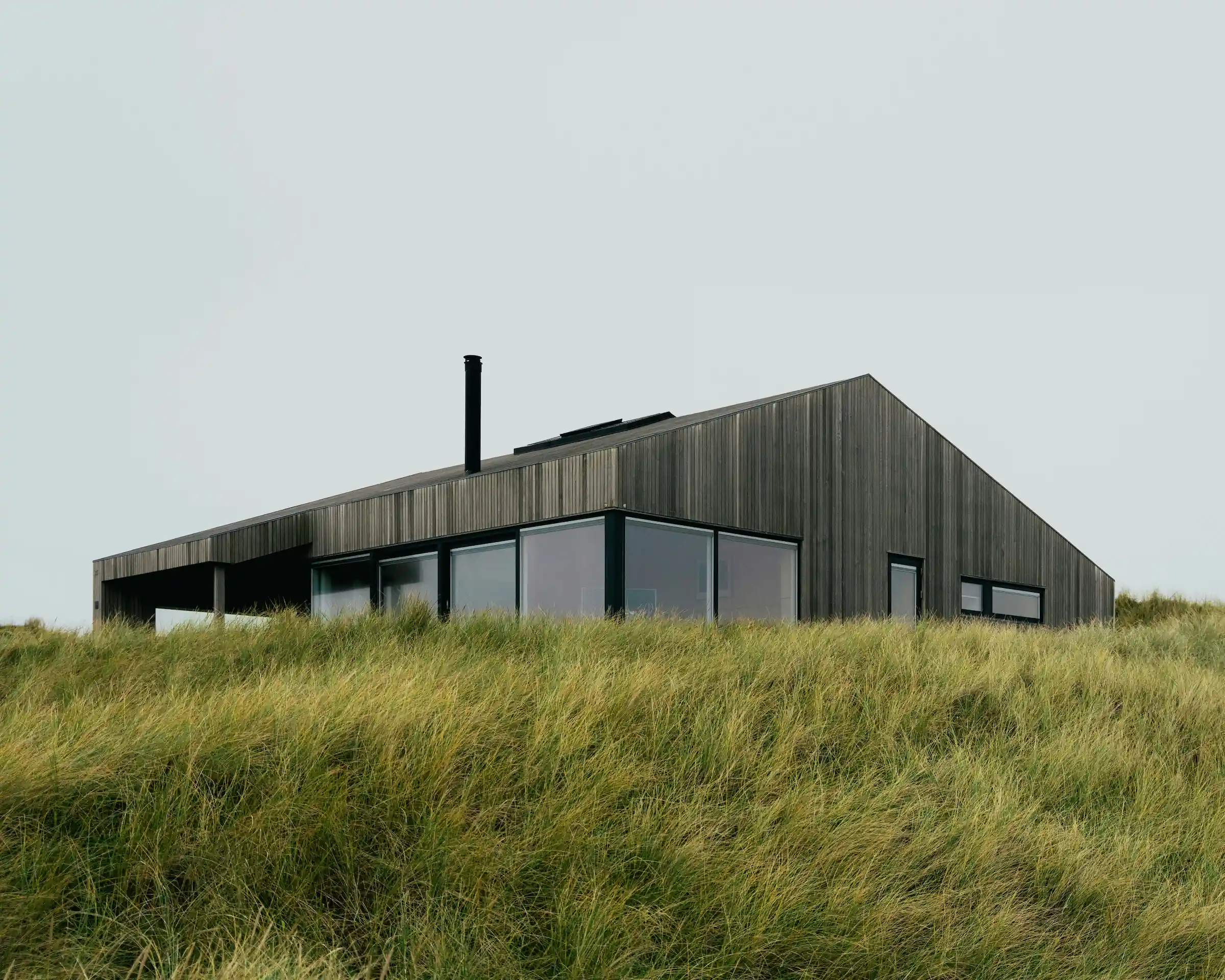 Modern interior entrance with floor-to-ceiling glass walls and warm timber cladding overlooking landscape