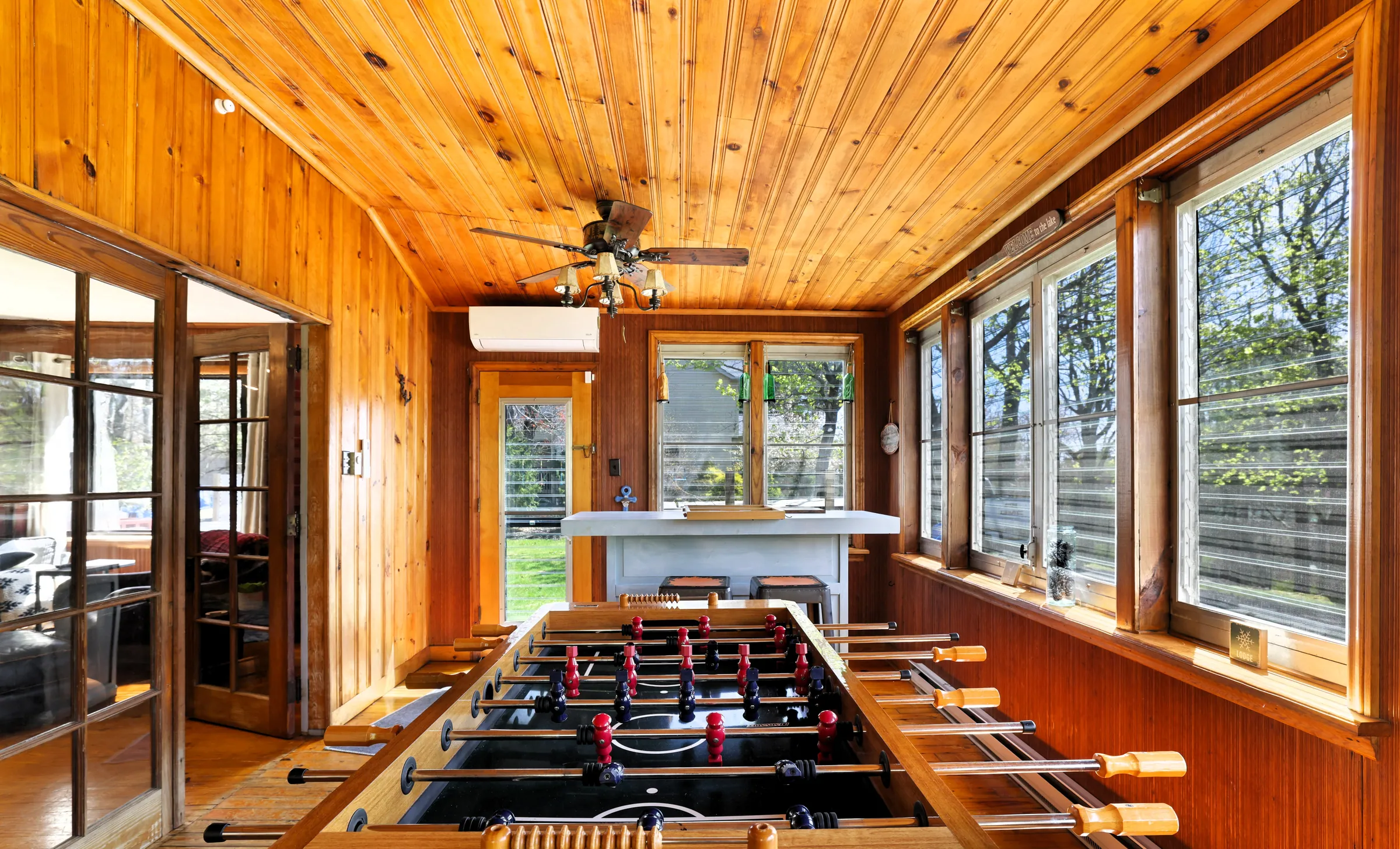 Sunroom game area with foosball table, pine ceiling and window walls at DeerPath Crossing