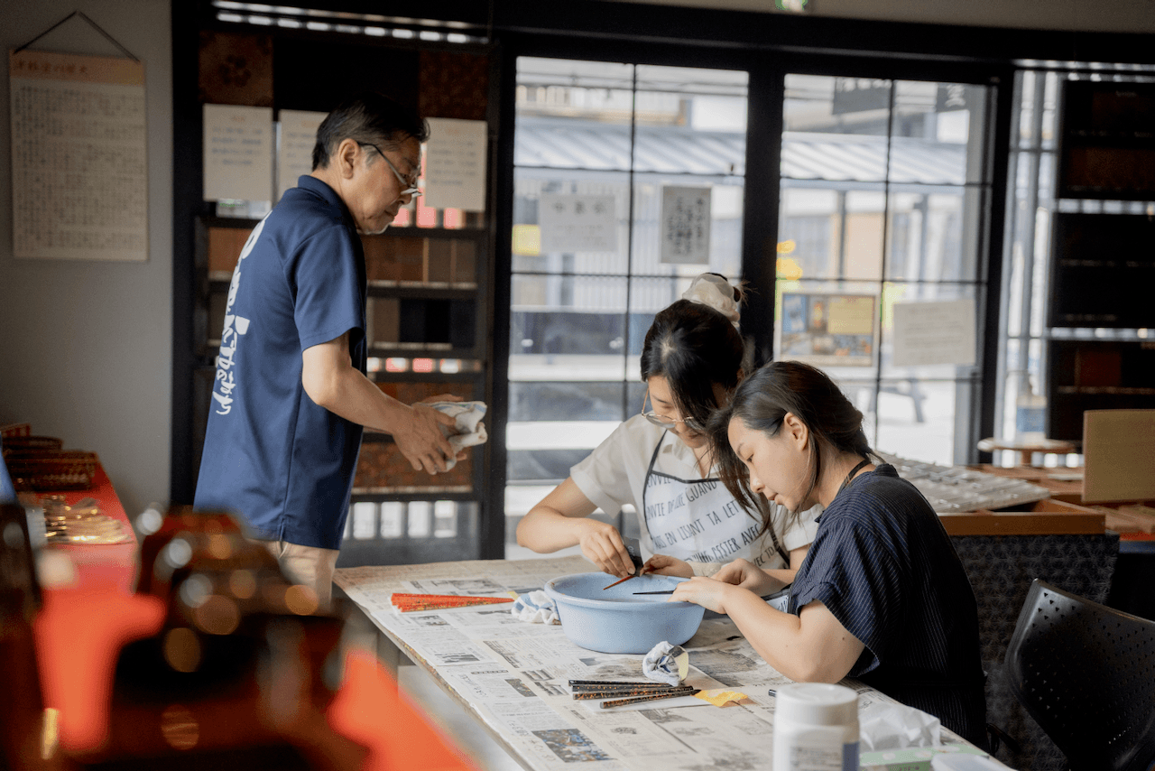 Craftsman teaching students how to make lacquerware chopsticks