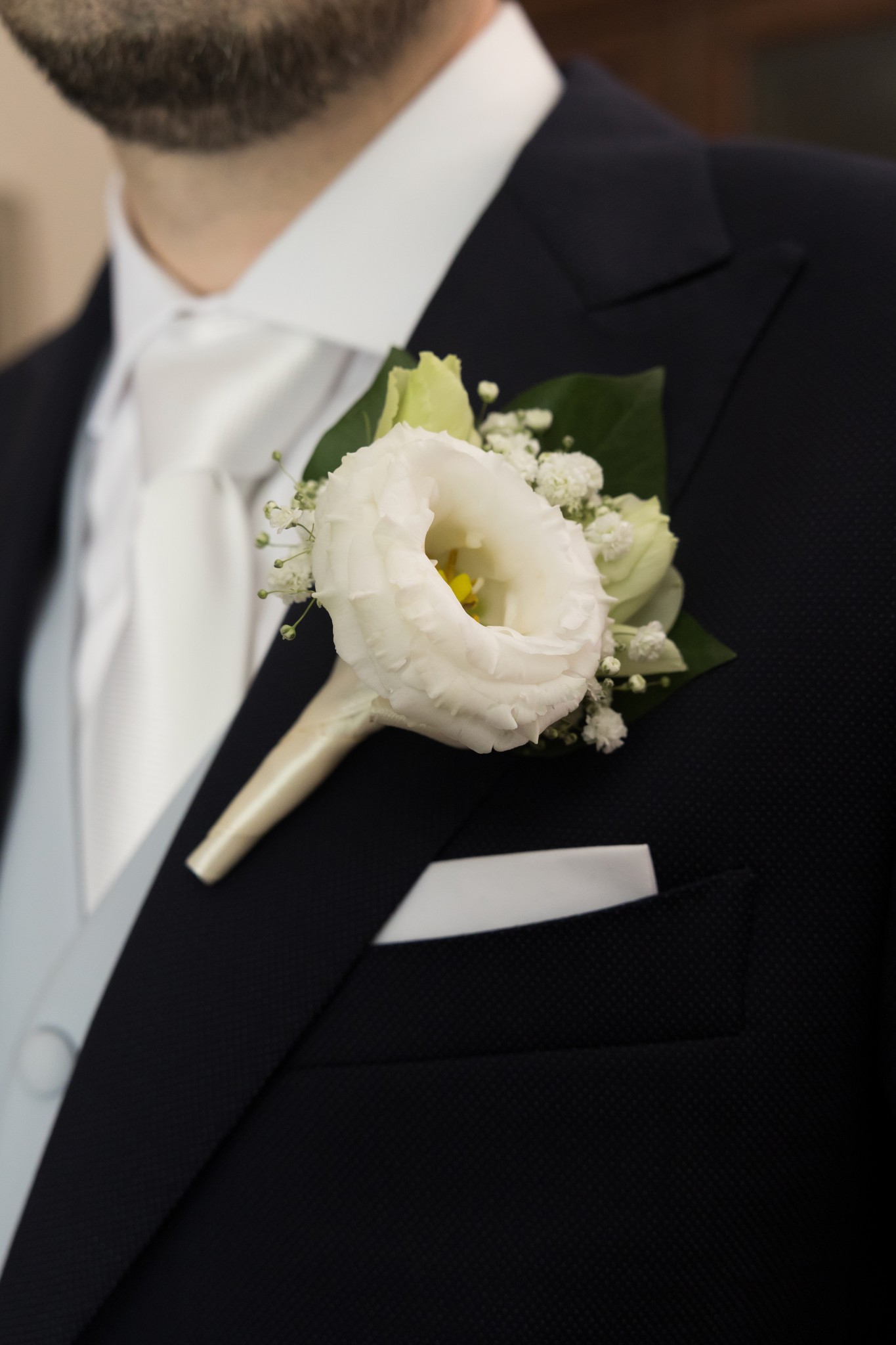 Sposo in completo blu con bottone d'oro bianco e gypsophila, dettaglio matrimoniale a Villa Peroni Riva
