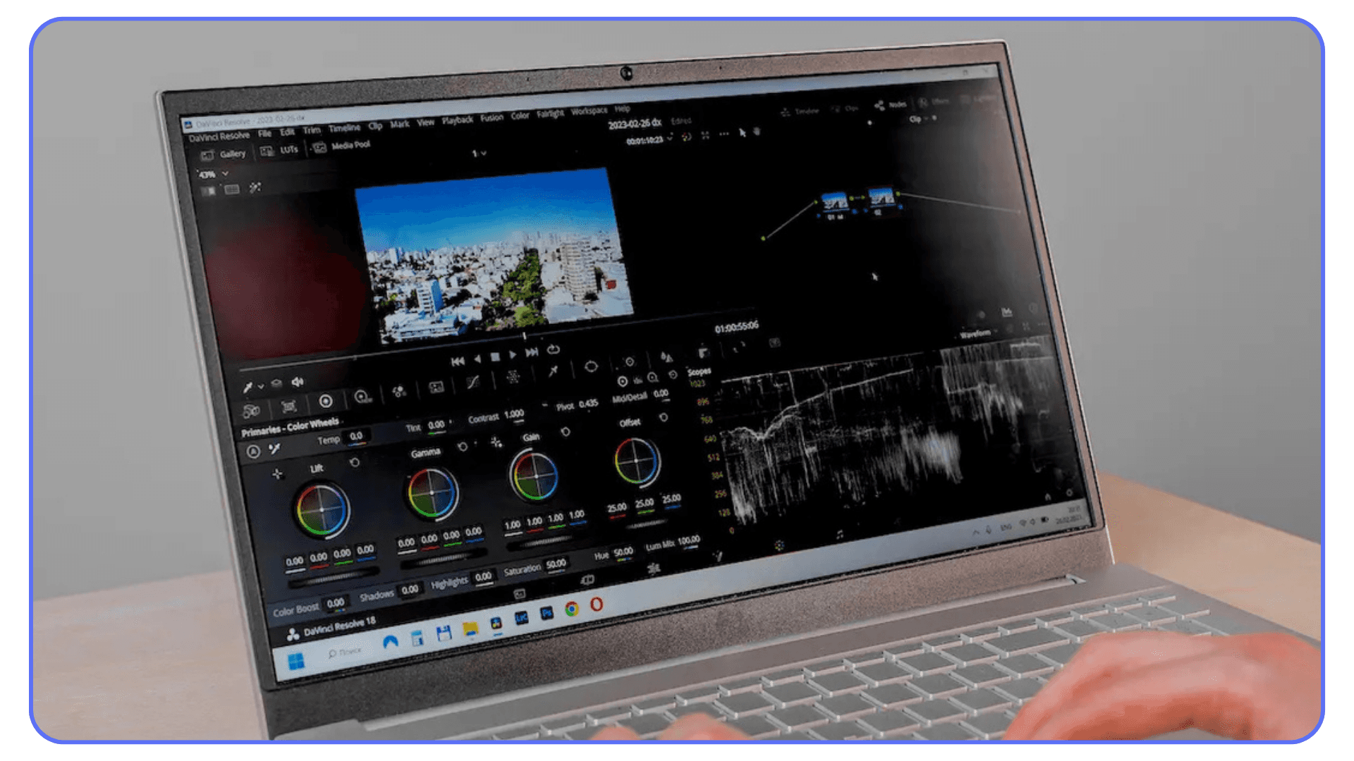 A Windows laptop running DaVinci Resolve with color wheels, scopes, and a basic node tree visible on screen.