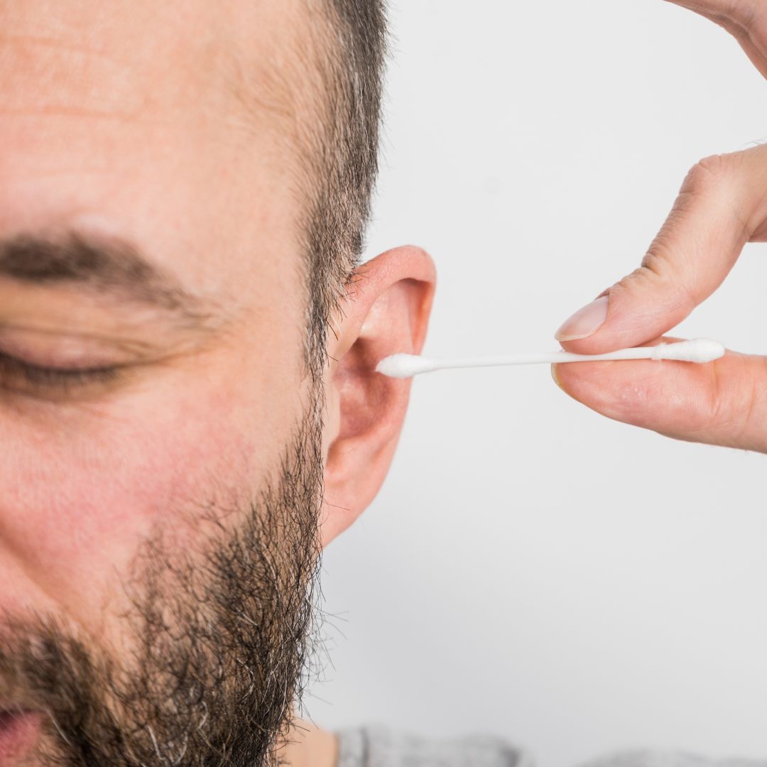 man inserting q tip into ear