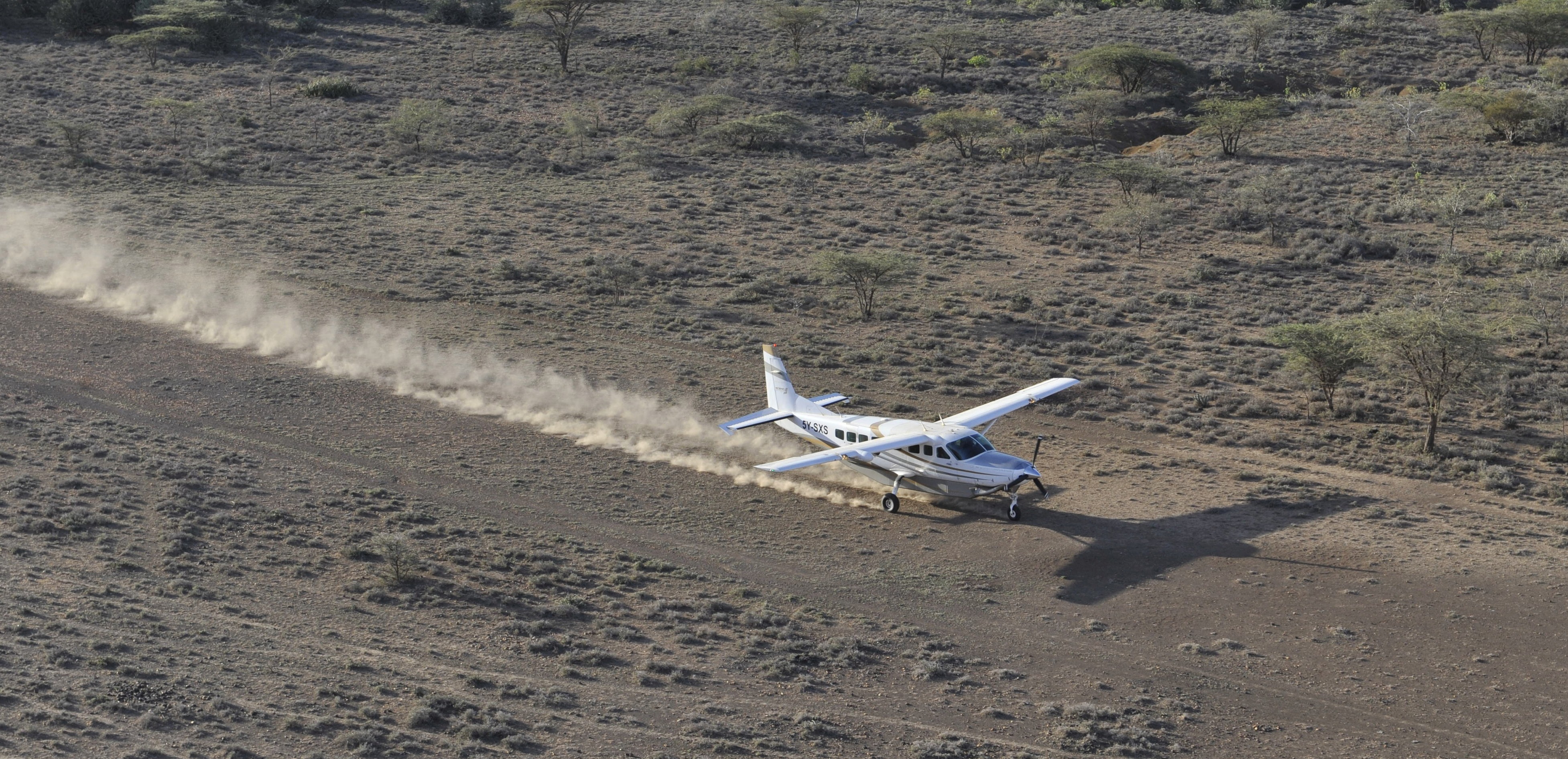 A bush plane trailing dust as it departs a remote safari airstrip