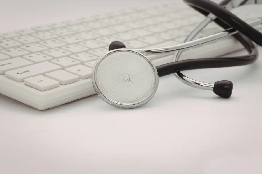 Stethoscope resting against a white computer keyboard symbolizing digital healthcare and online medical services.