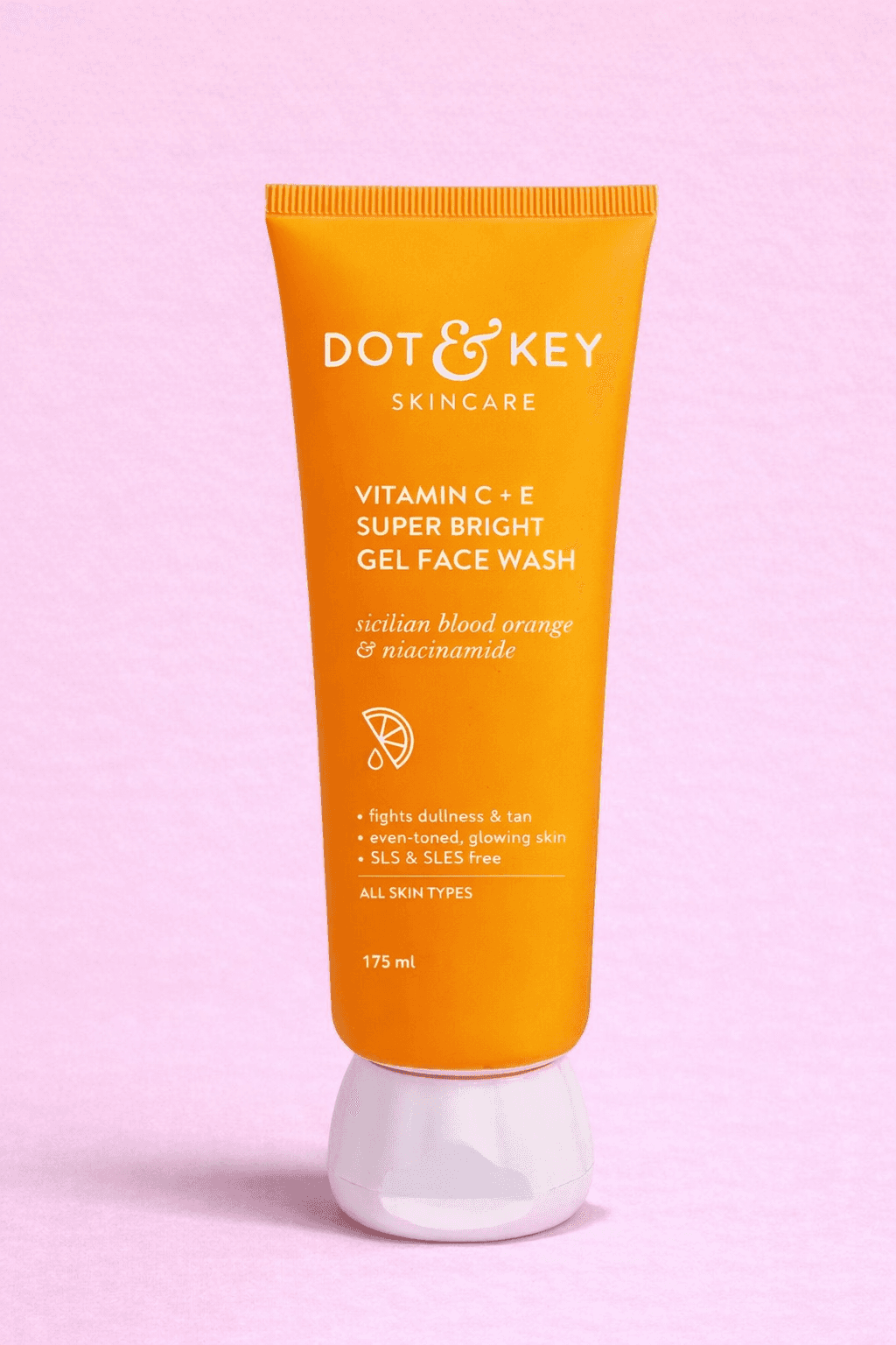 Smiling young woman with long hair standing against a dark green background, holding a finger to her chin.