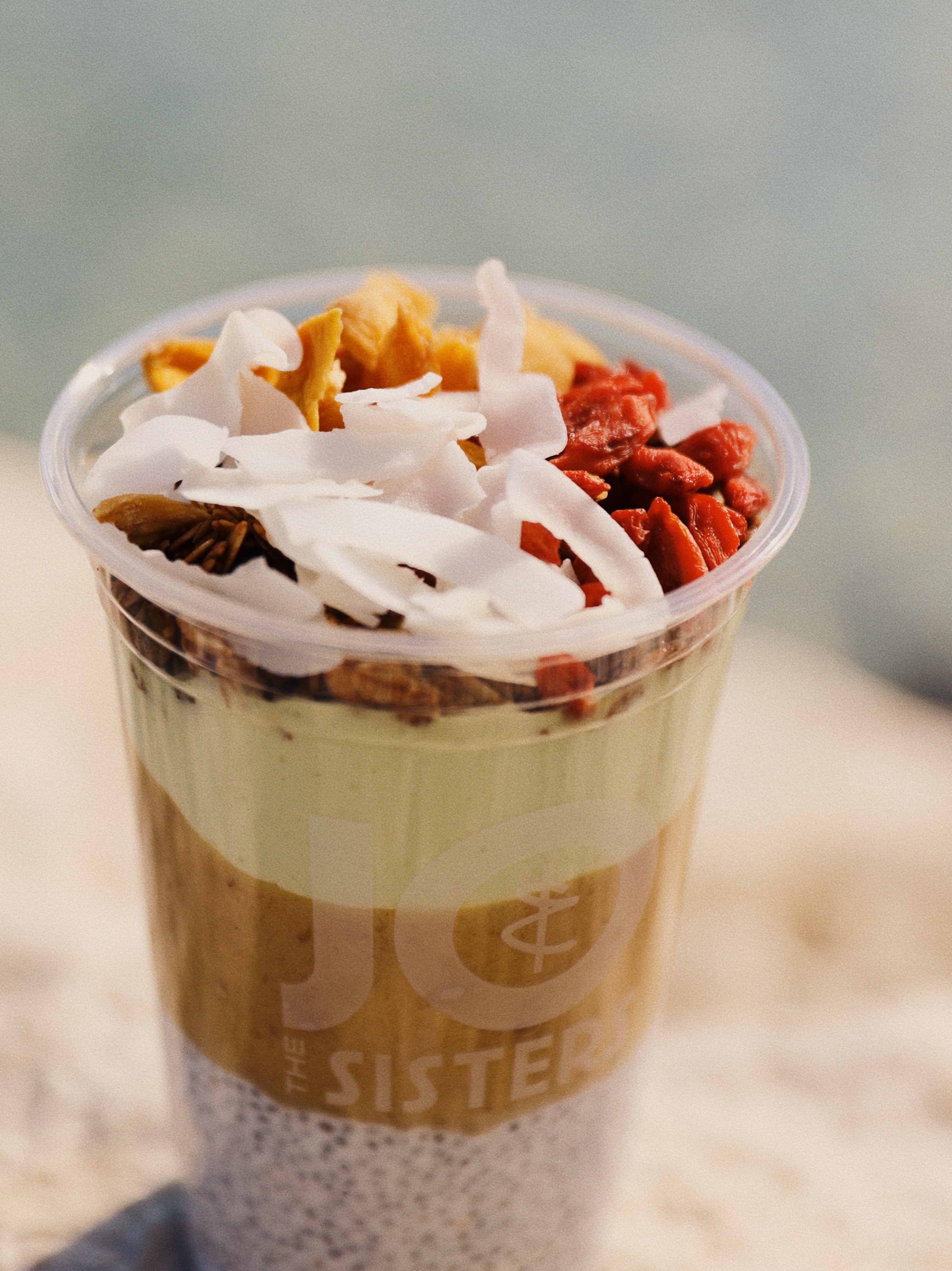 Jo & The Sisters smoothie bowl topped with coconut flakes, goji berries, and granola in a grab-and-go cup