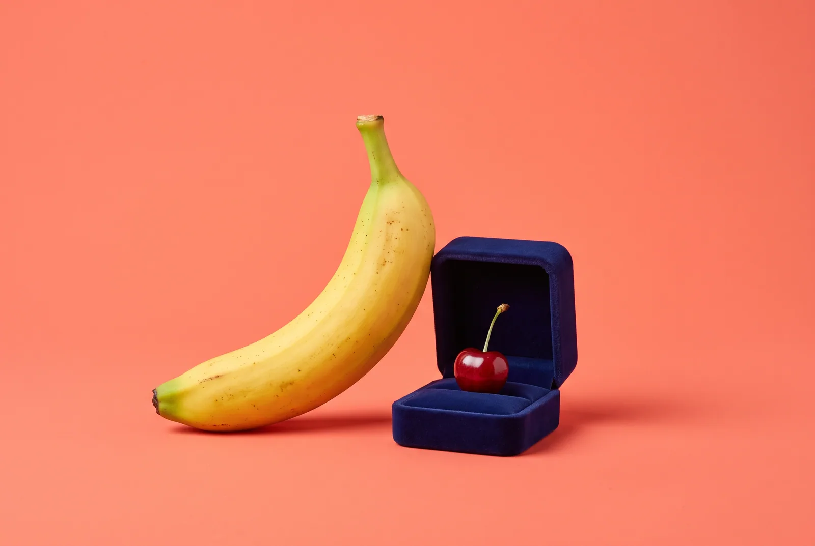 A velvet ring box holding a cherry before a banana, a playful image for how to ask someone to be your accountability partner