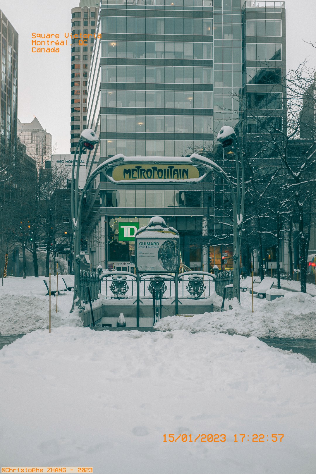 Entrée Art nouveau du métro Square-Victoria enneigée, devant des tours de verre.