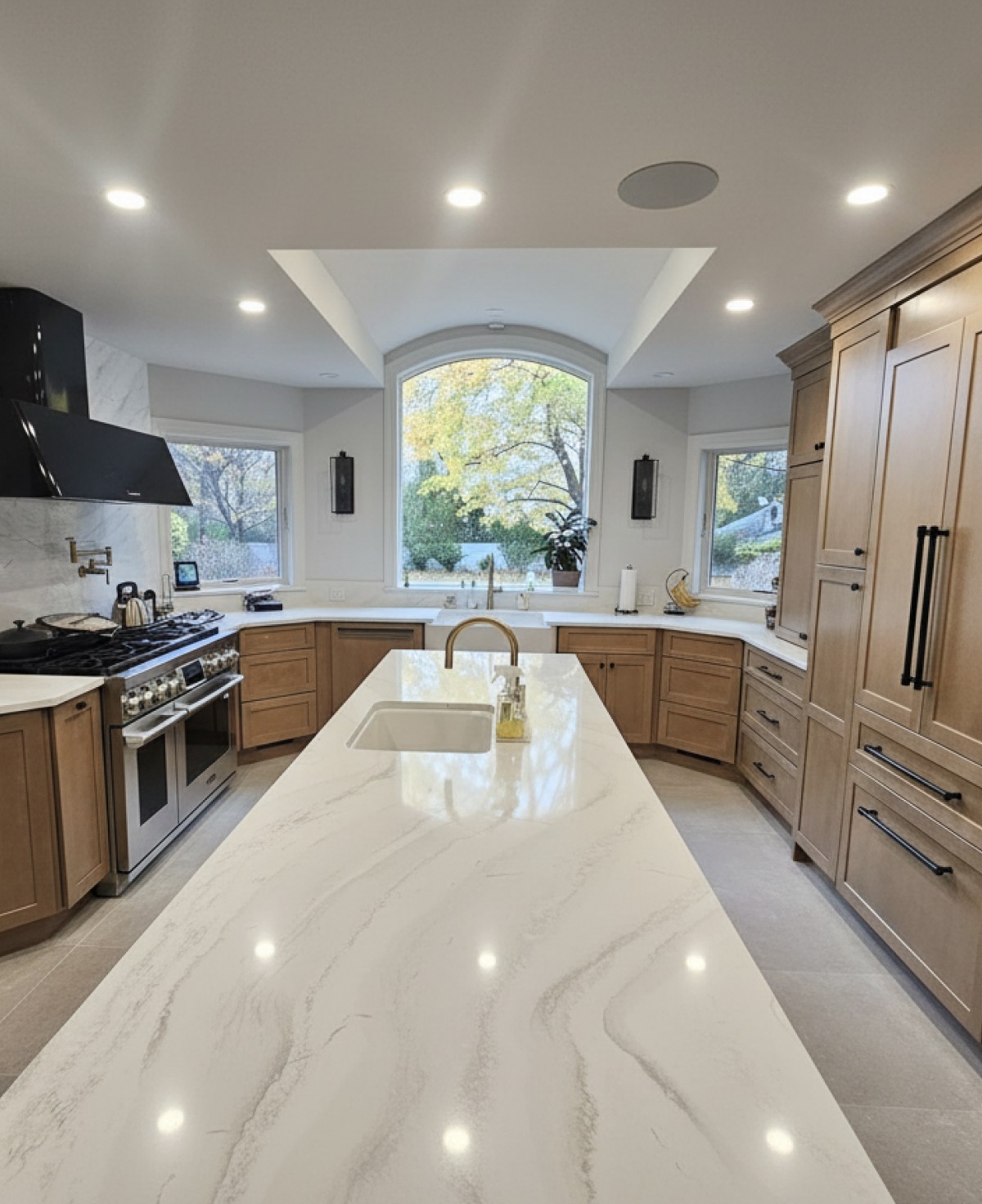 Kitchen renovation with custom wood cabinetry, quartz island, and modern appliance layout