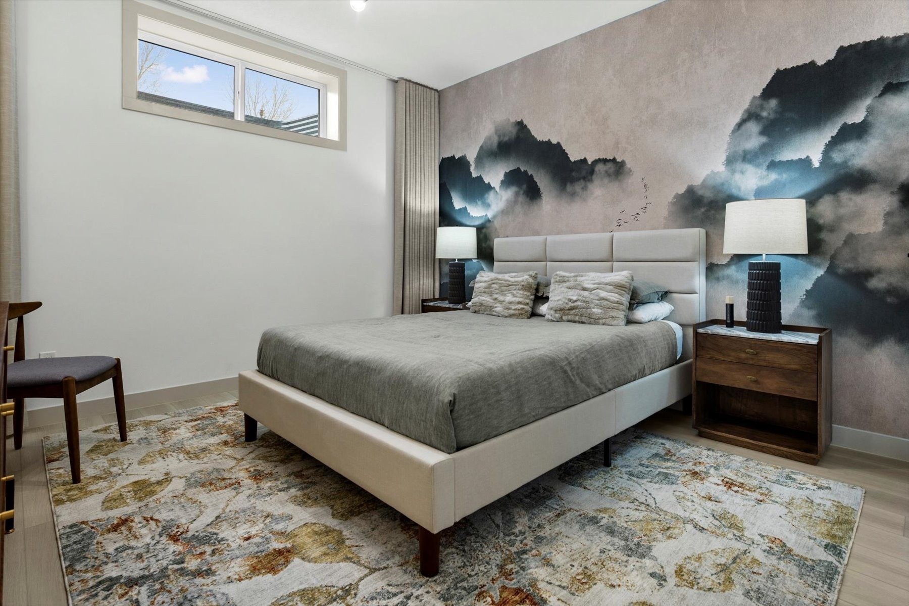 Legal suite bedroom after: misty mountain mural wallpaper behind an upholstered bed, walnut nightstands and a high window