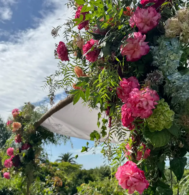 Arco floral al aire libre con rosas y follaje verde para evento botánico o ceremonia, diseñado para transmitir frescura y celebración natural.