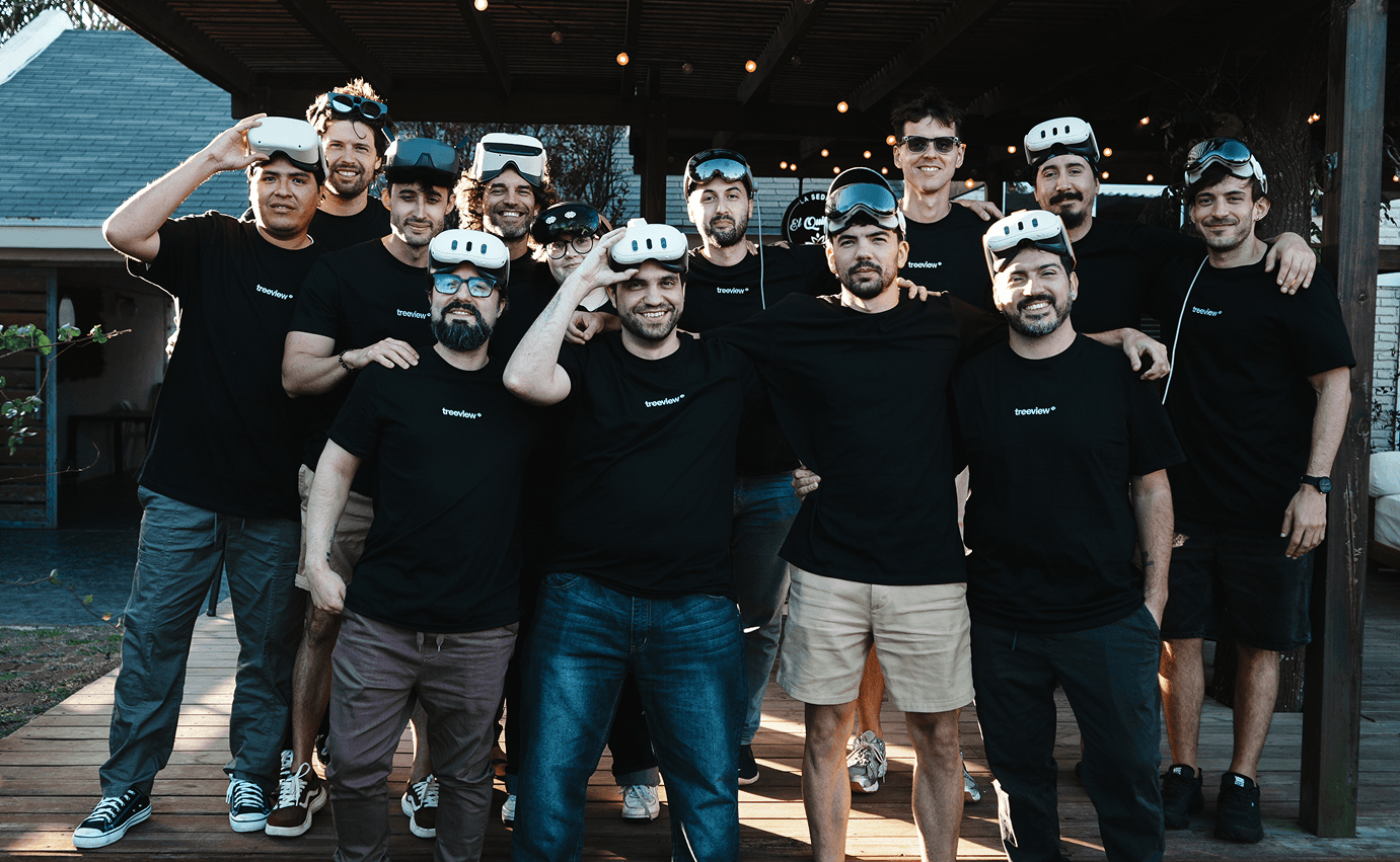 Treeview team photo with fourteen members wearing branded black t-shirts and holding Meta Quest and Apple Vision Pro headsets at an outdoor venue