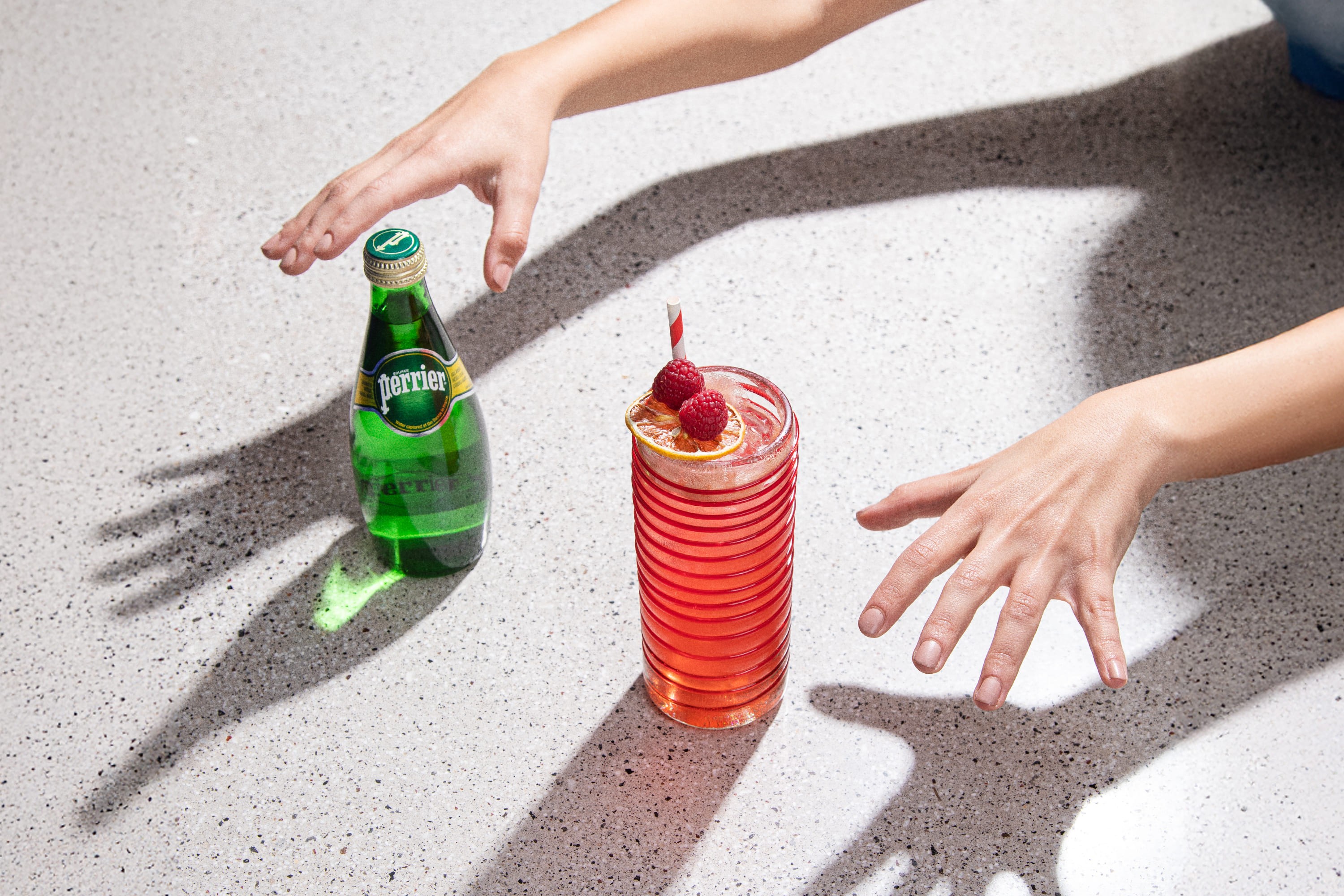 perrier bottle with cocktail and hands