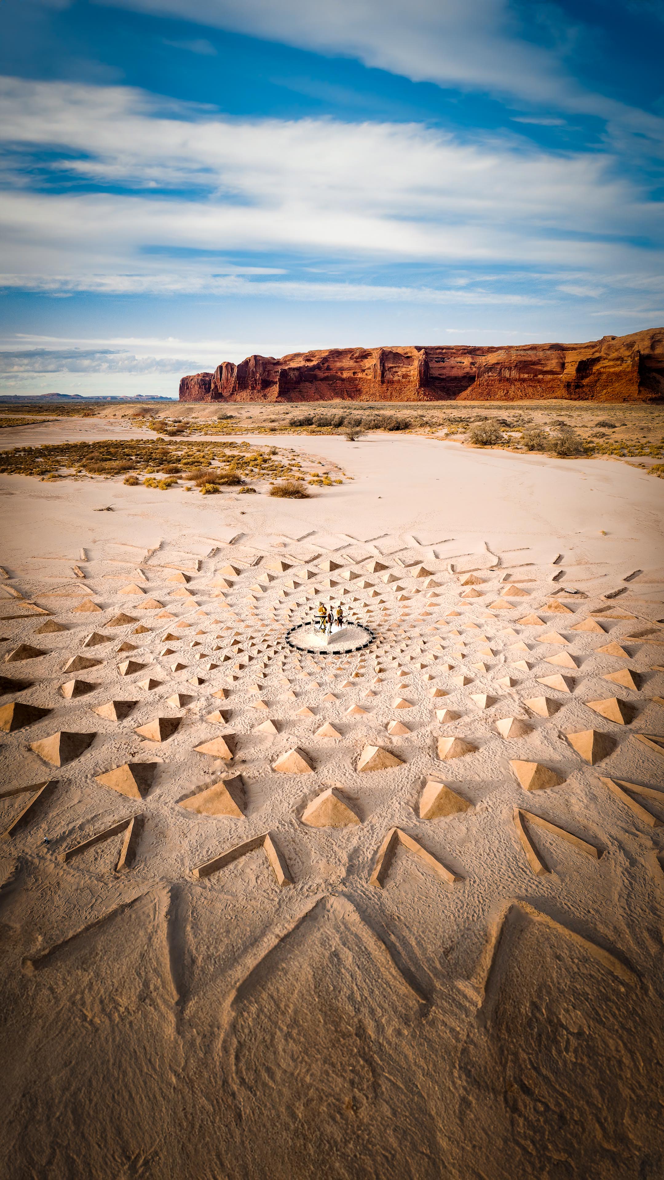 A drone photo of land art made out triangles in front of red rock formations in Arizona