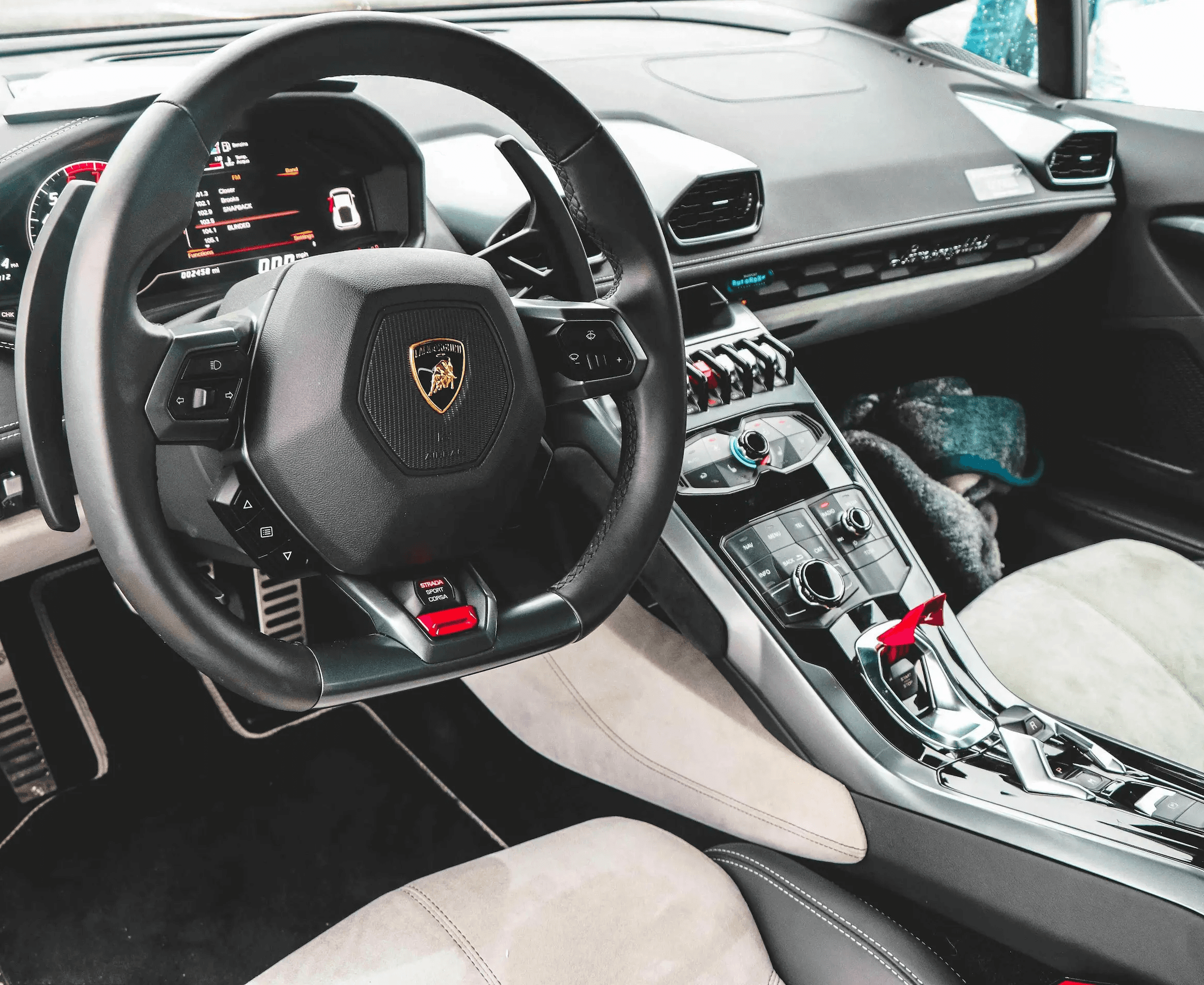 Detailed interior of a Lamborghini featuring a deep-cleaned steering wheel, center console, and upholstery as part of a premium full interior and exterior detailing package in Houston.
