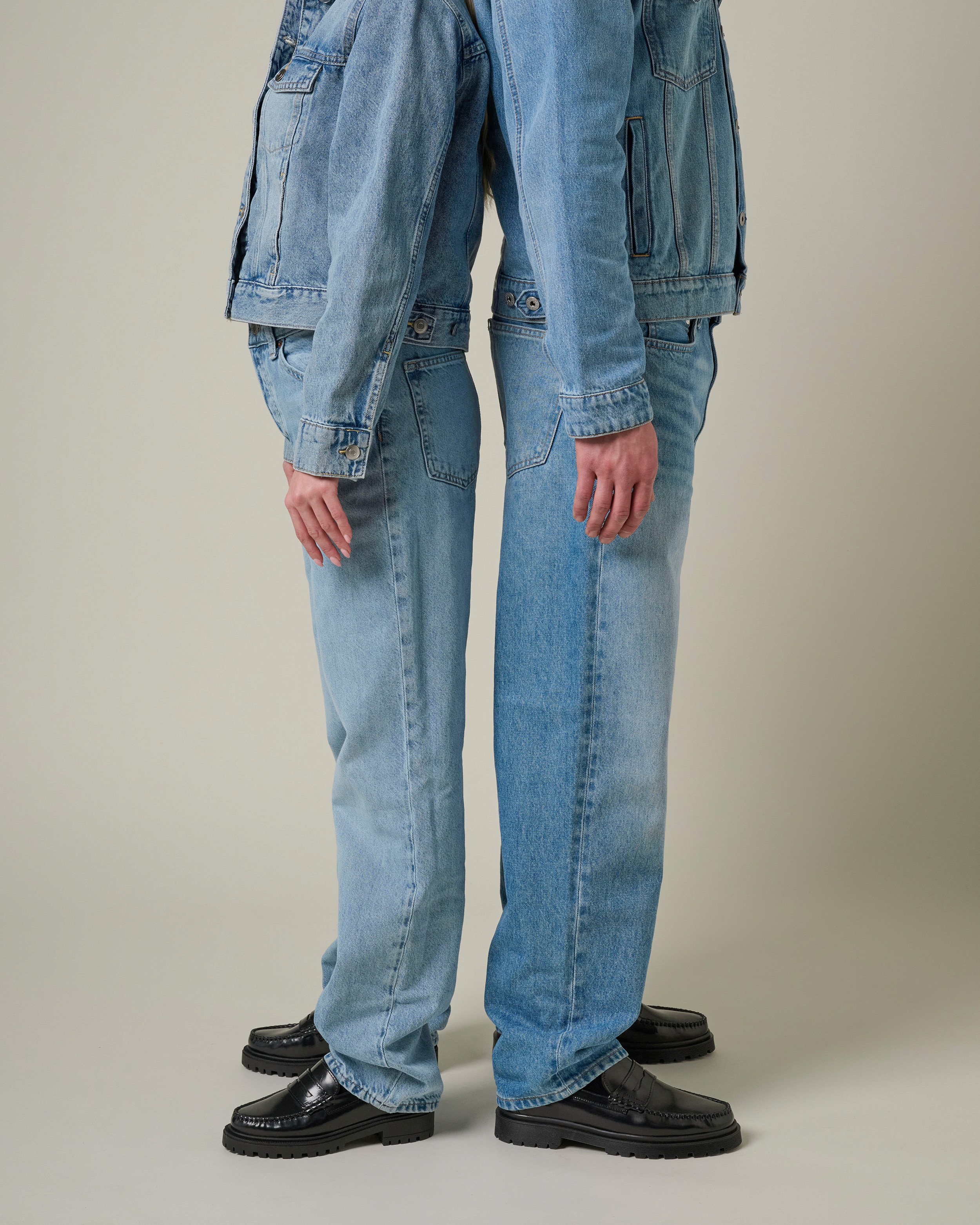 Le bas de la silhouette de 2 personnes qui portent du denim et des mocassins noirs