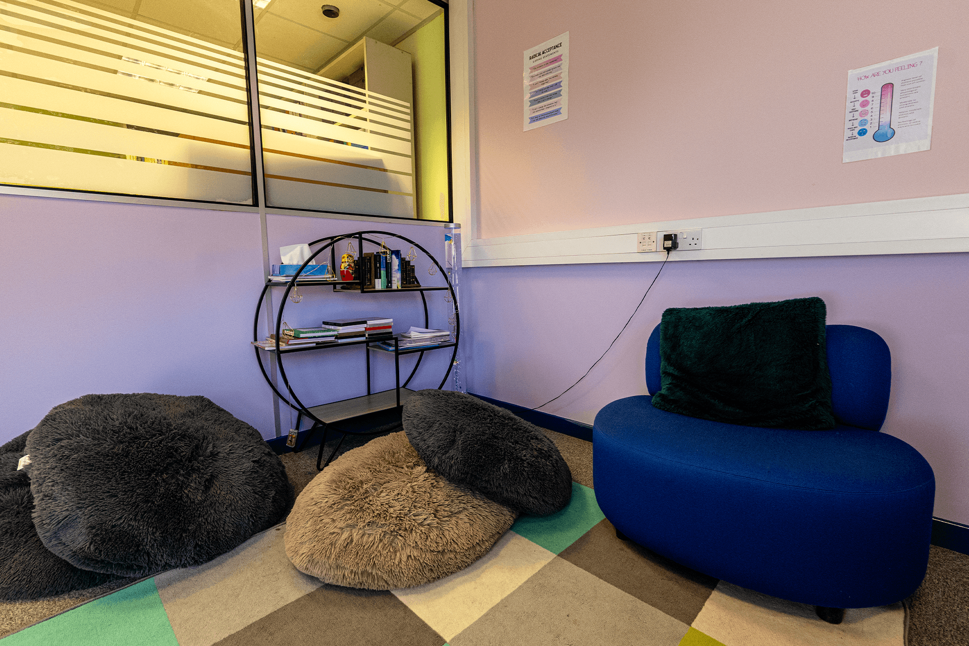 Reading area furnished with shelf full of various books and a visible electrical outlet, designed for comfortable reading and study