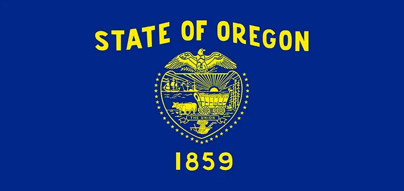 Flag of Oregon with a blue background, featuring a yellow state seal depicting an eagle, a covered wagon, and the text "State of Oregon 1859."